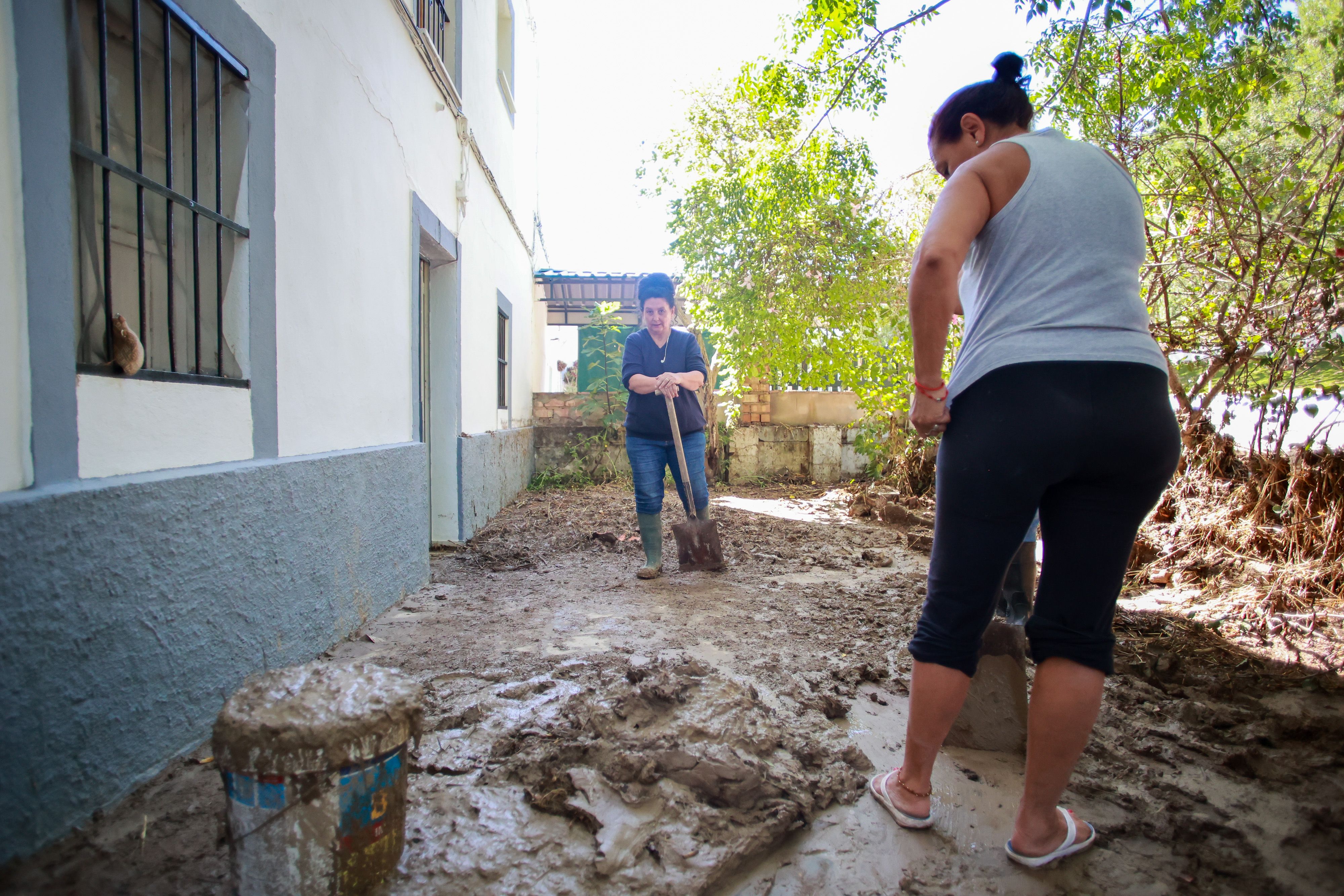 Familiares de Vicente achicando agua y barro de sus casas.