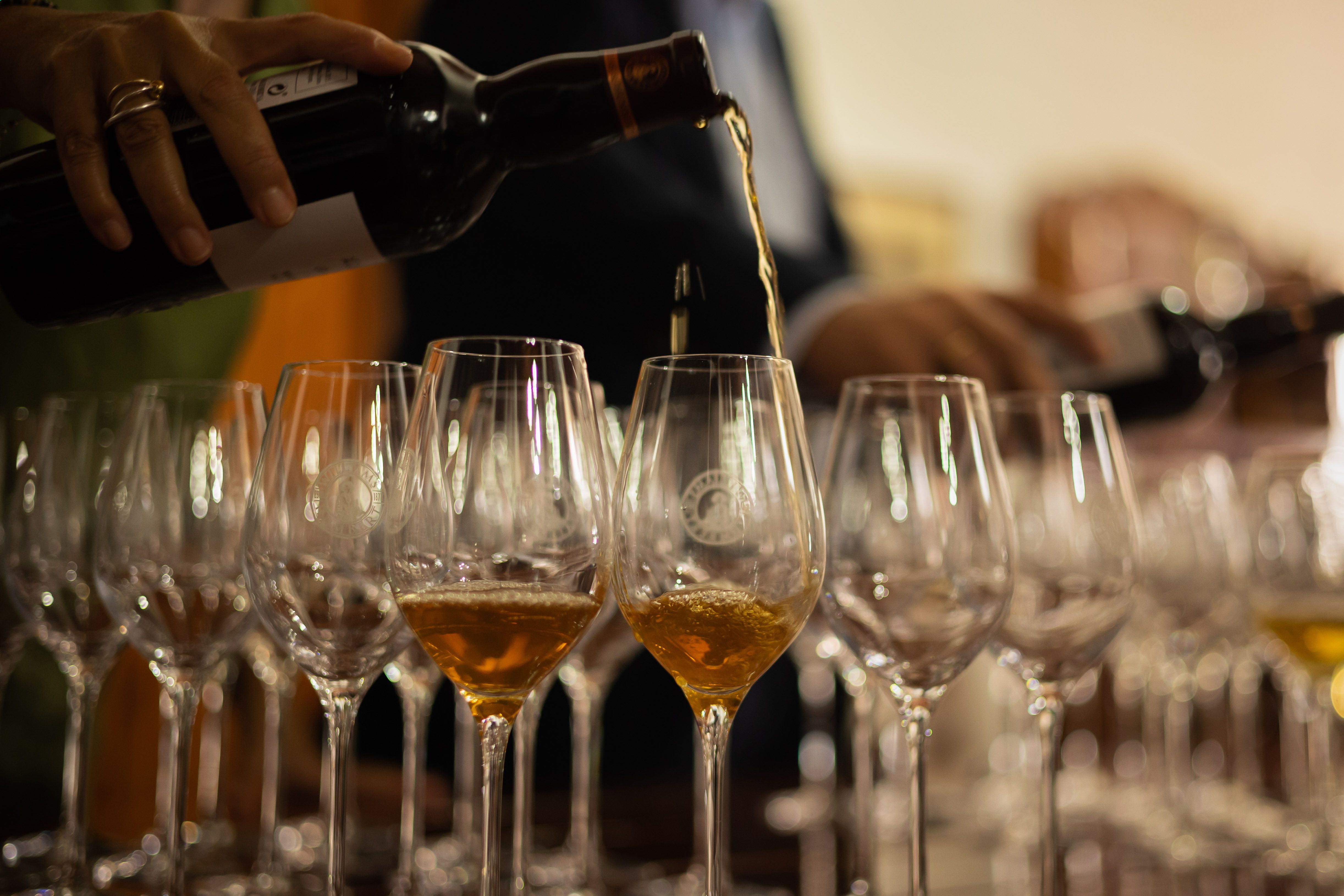 Una persona sirve varias copas de vino en una cata. Una persona sirve varias copas de vino en una cata.