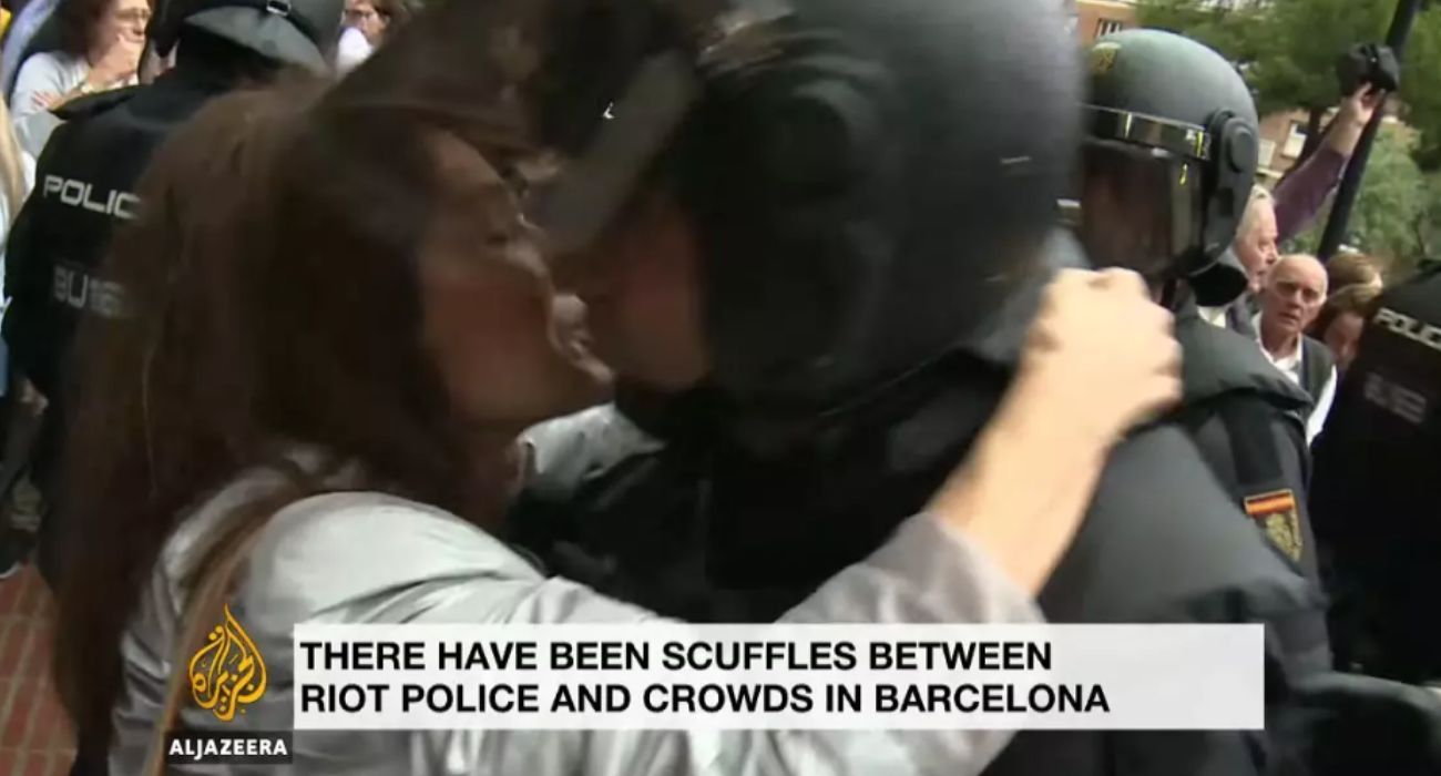 Momento del beso de una manifestante a un policía durante las cargas del 1 de octubre de 2017 en Barcelona.   FOTO: AL JAZEERA