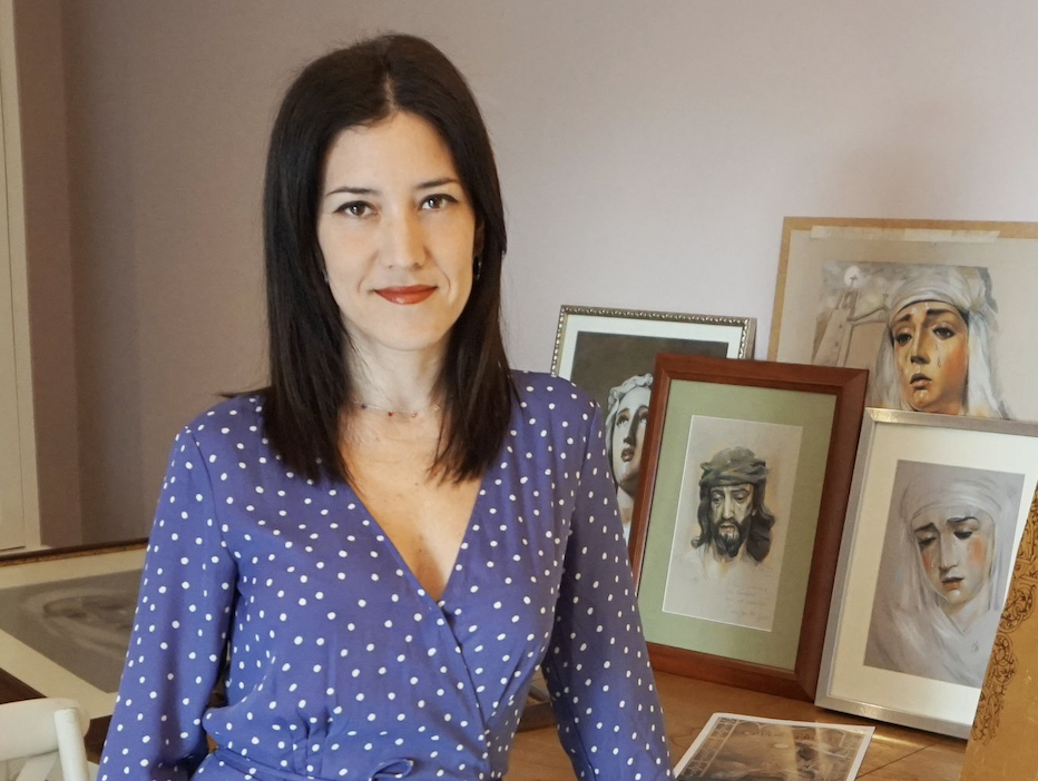 Inmaculada Peña posando ante varios retratos de imágenes titulares de hermandades.