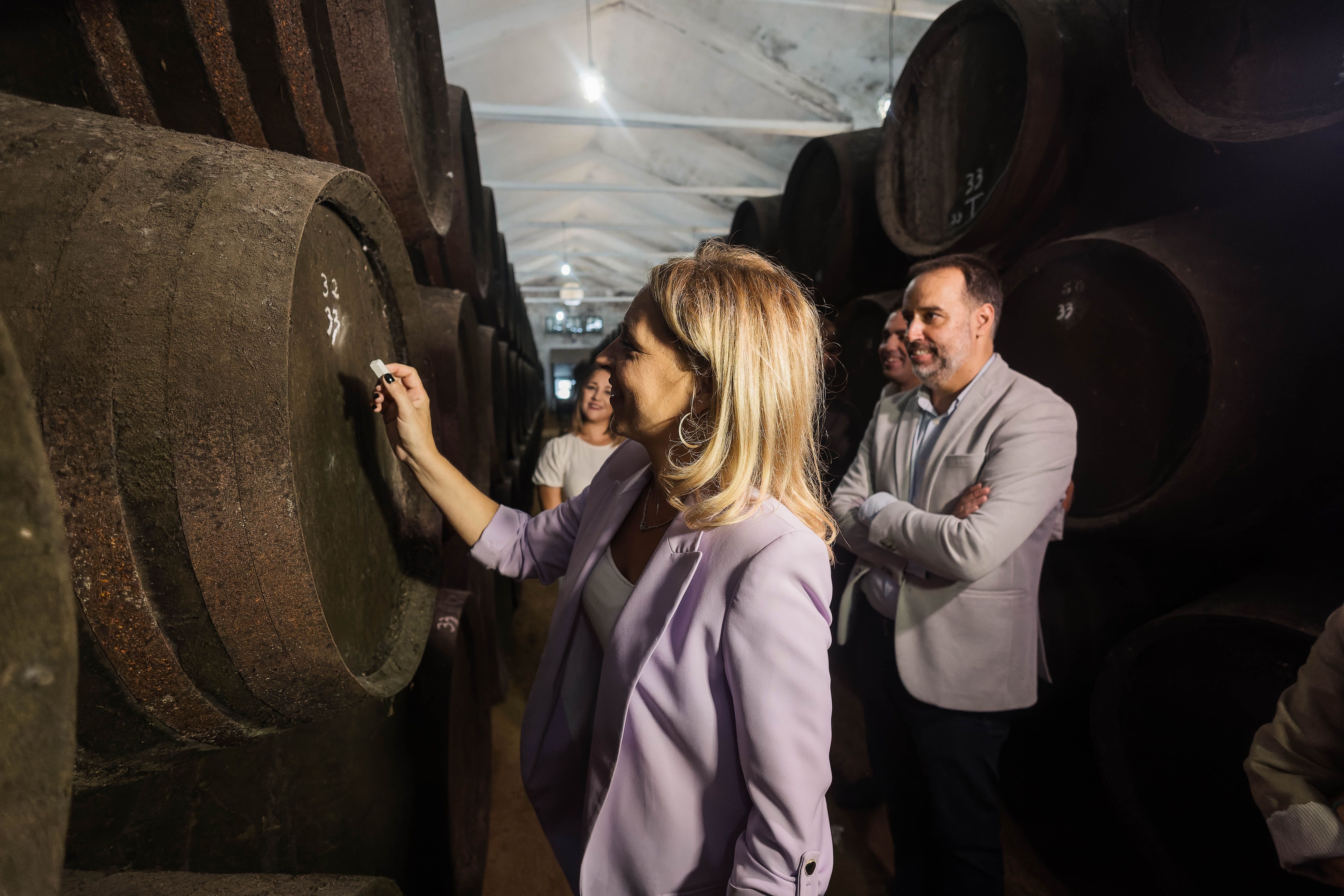 La presidenta de Diputación de Cádiz, Almudena Martínez, firmando una bota en la cooperativa Nuestra Señora de Palomares bajo la mirada del alcalde de Trebujena, Ramón Galán.