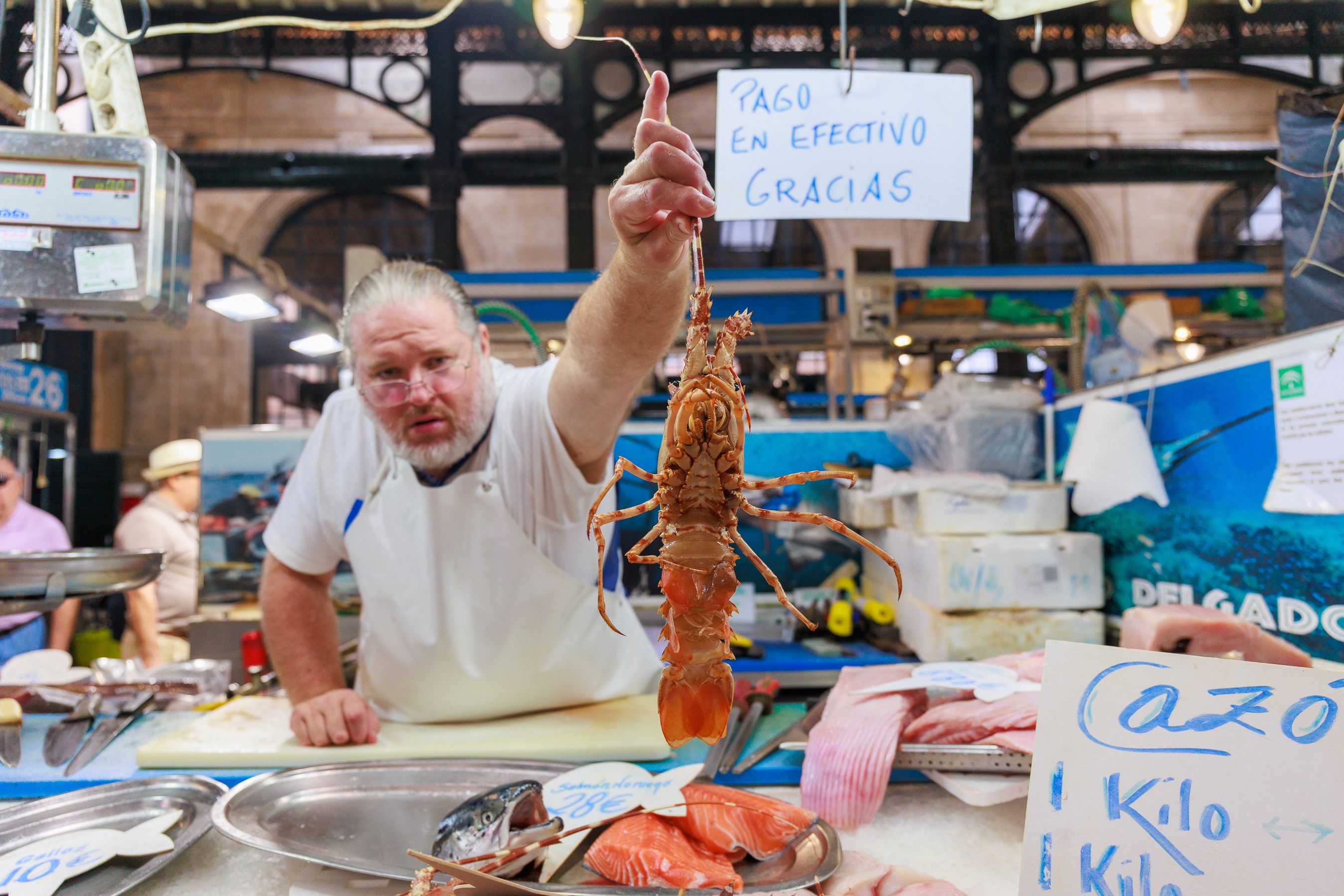 Un pescadero de la Plaza mostrando una langosta.