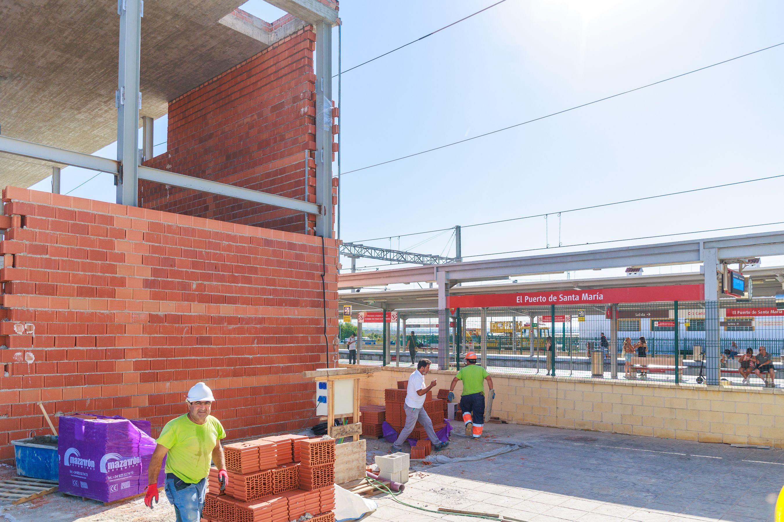 Varios obreros realizan su trabajo junto a la estación de tren.