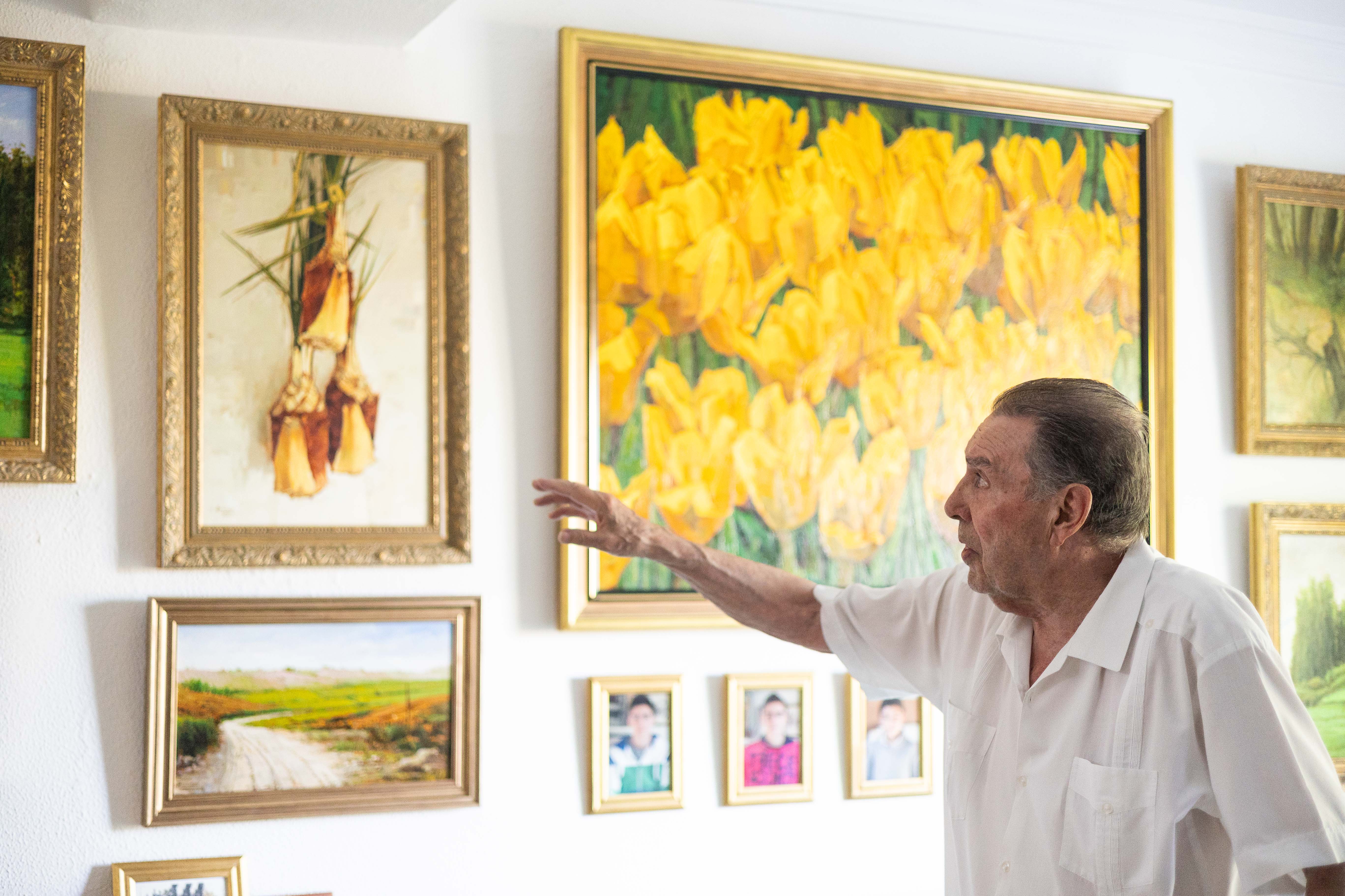 Antonio Higuero: "El pintor necesita tiempo y soledad". En su casa ante decenas de cuadros, como los que señala.