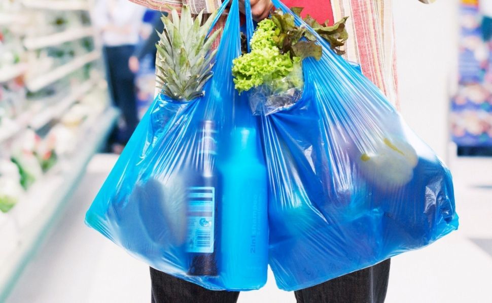 Un usuario, llevando su compra en bolsas de plástico. 