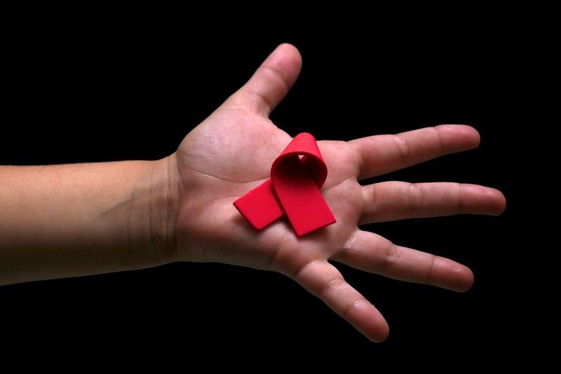 Una mano, con el lazo rojo que caracteriza a la lucha contra el sida. 