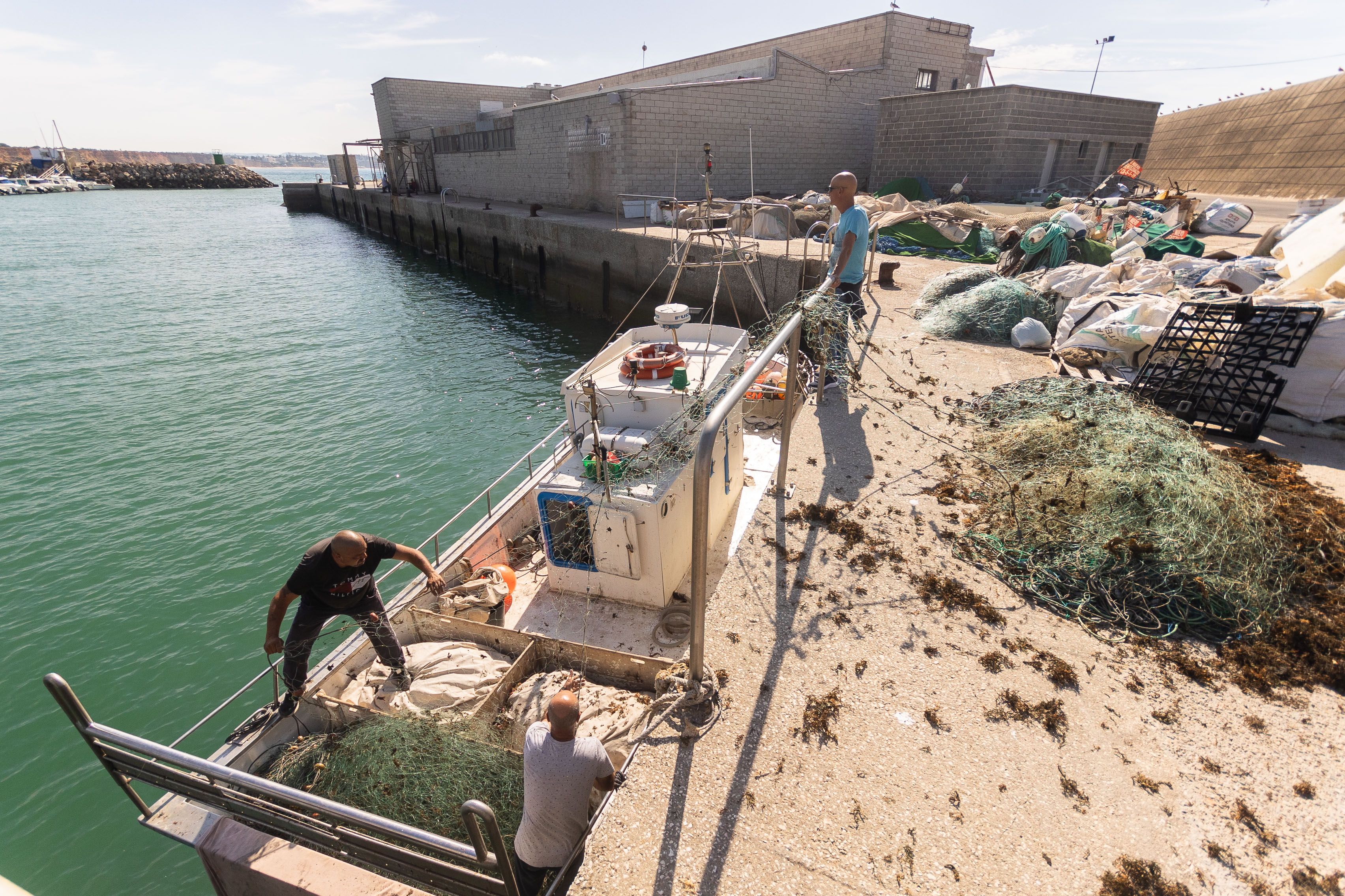 Pescadores reparan redes en el puerto de Conil este primer jueves de octubre.