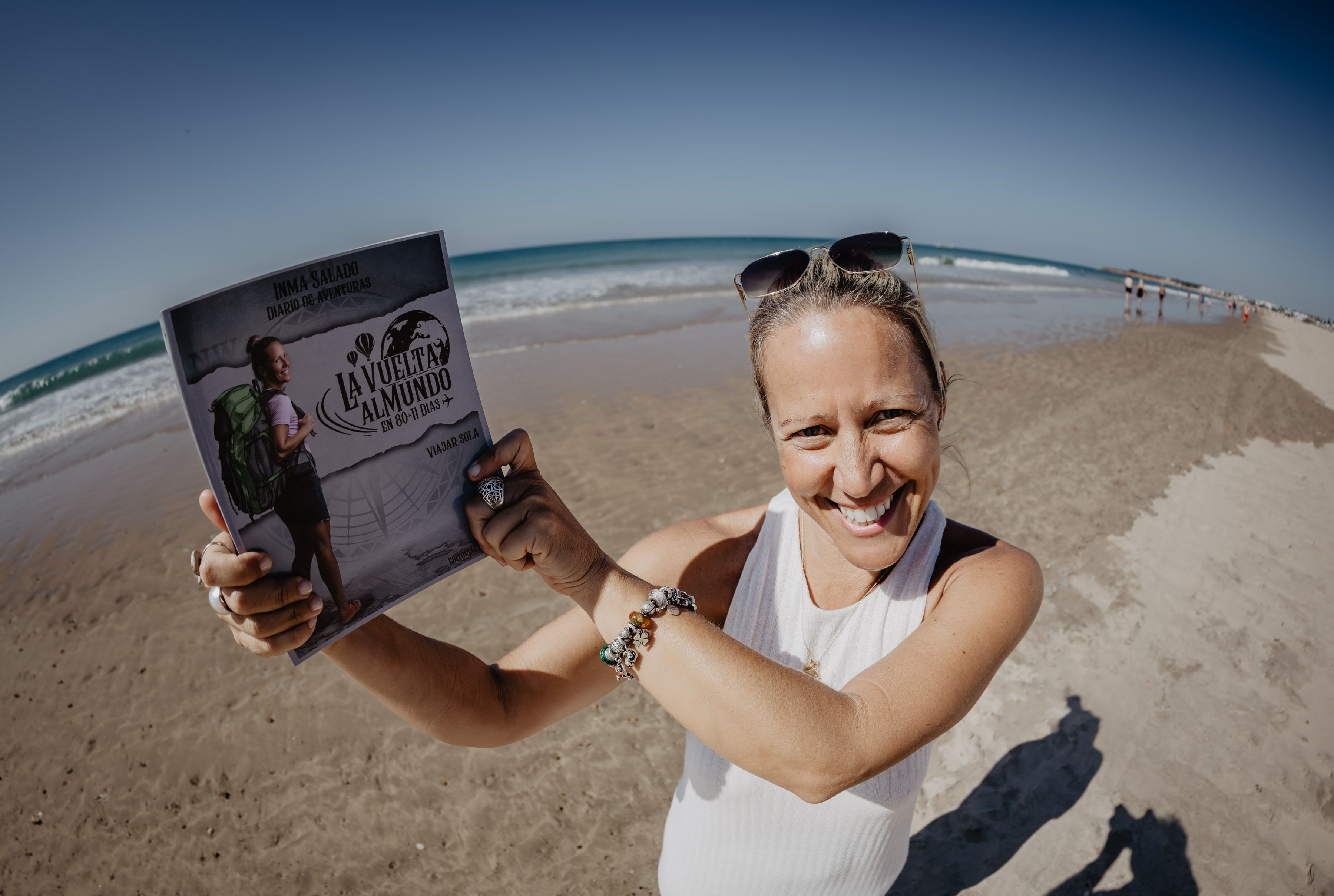 Inma Salado, en la orilla de La Barrosa, con un ejemplar de su 'Vuelta al mundo en 80+11 días'.