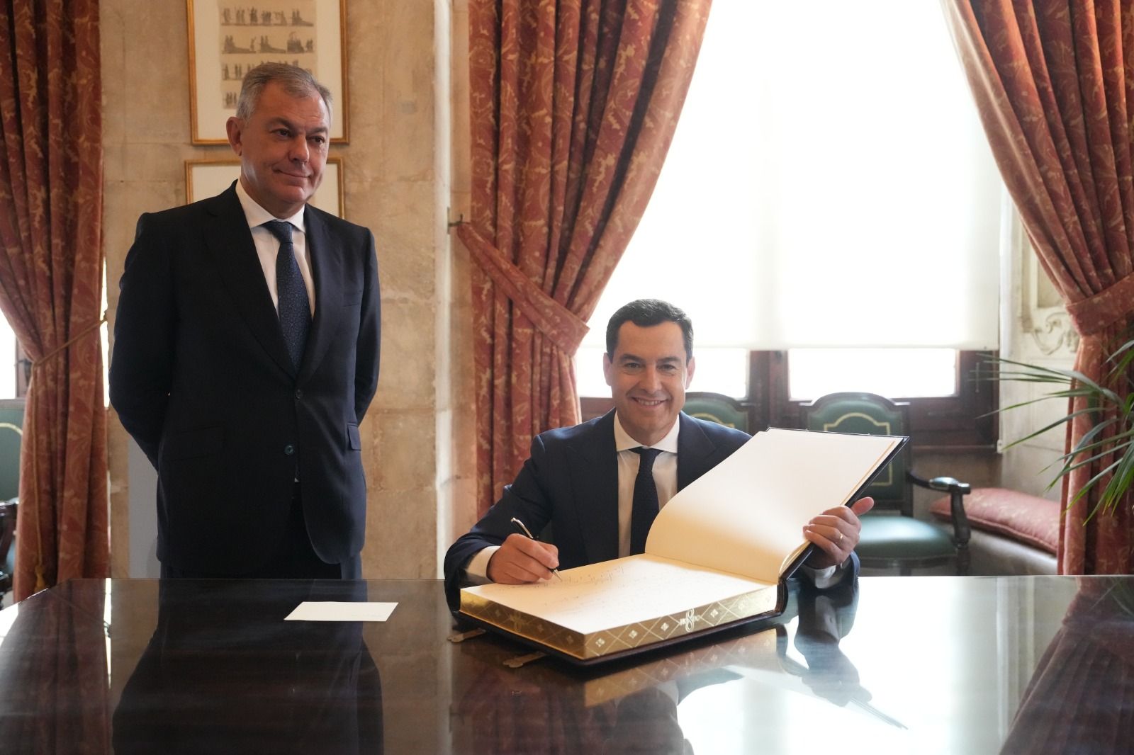 Moreno firma el libro de honor del Ayuntamiento de Sevilla ante la presencia de José Luis Sanz.