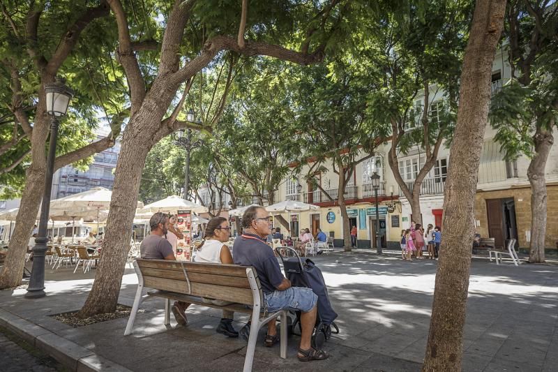 Vecinos sentados en un banco situado junto al perfil de la plaza del Mentidero que reabrirá al tráfico.