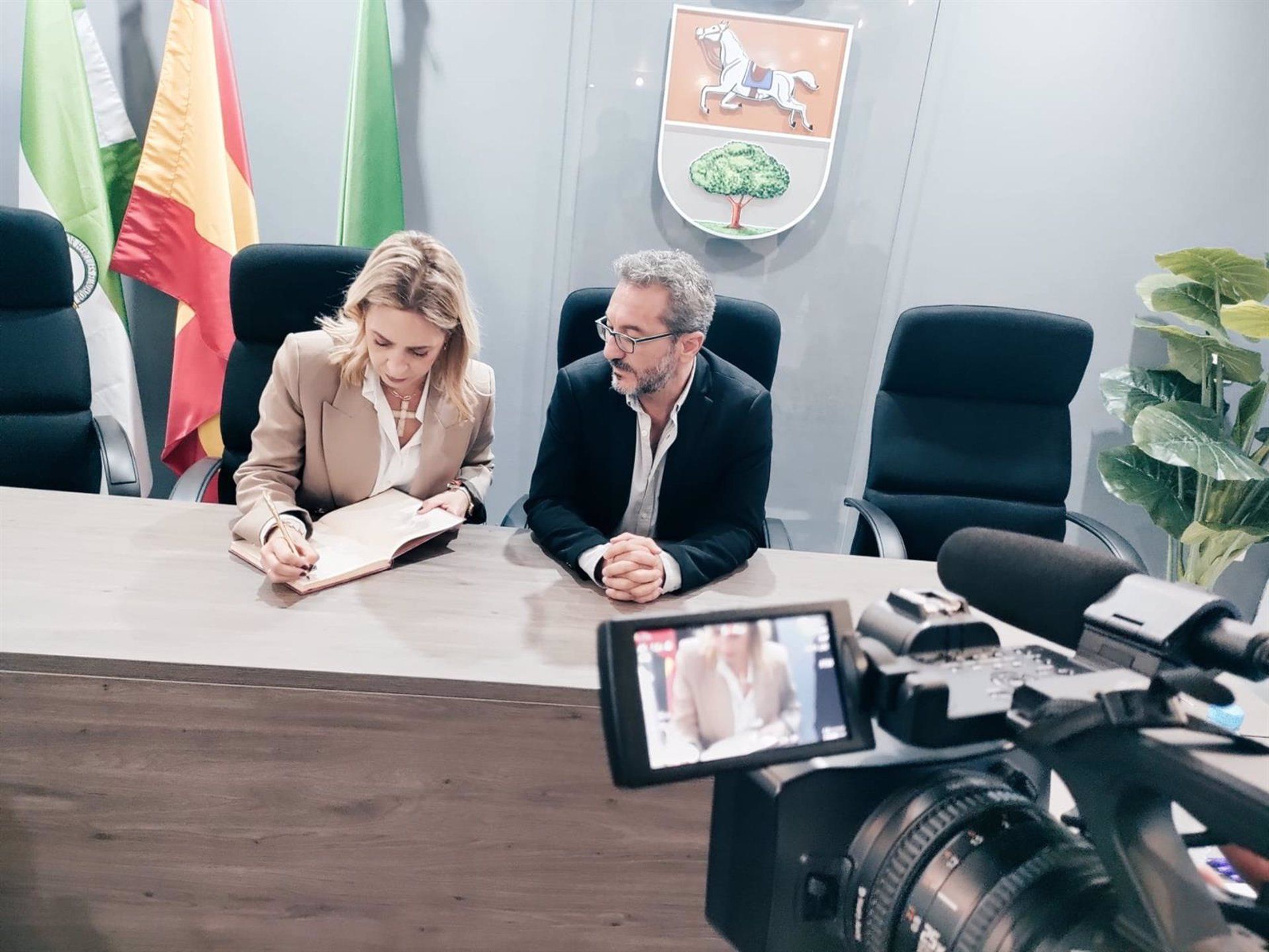 La presidenta de Diputación, Almudena Martínez del Junco, firma en el Libro de Honor del Ayuntamiento de Puerto Serrano, junto al alcalde.