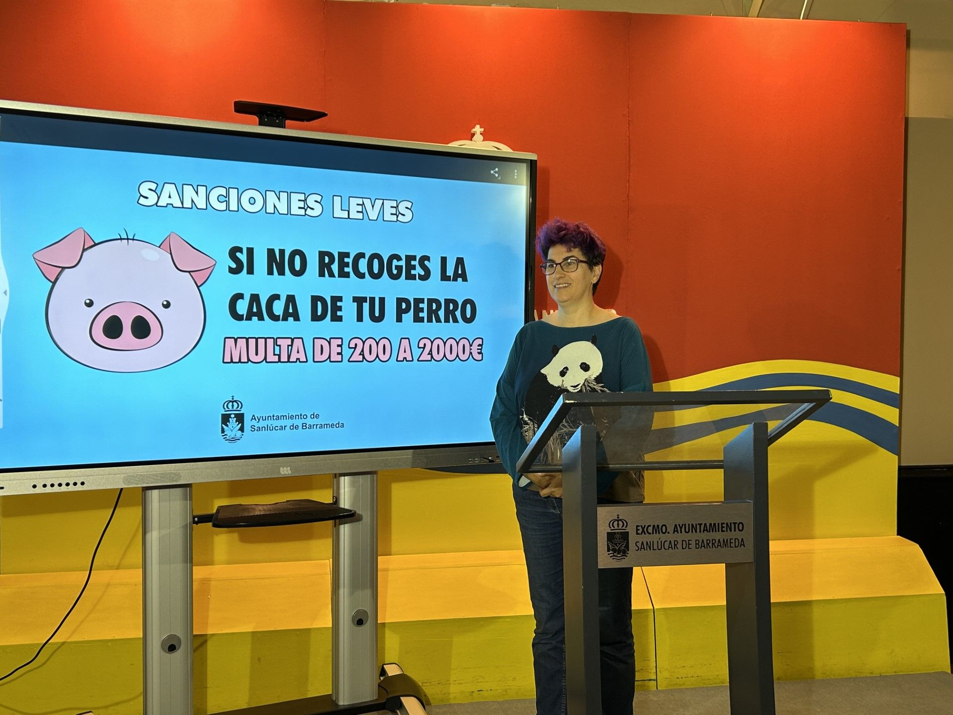 La delegada junto a una pantalla que expone la imagen central de la campaña. 