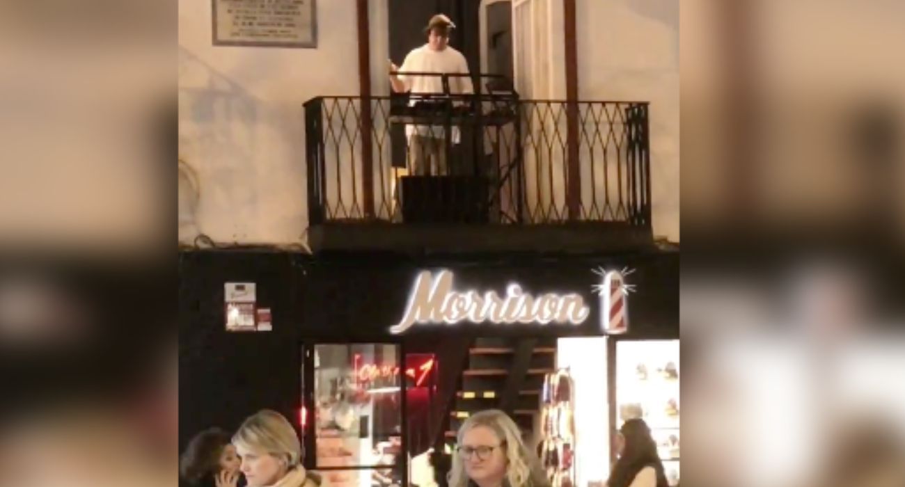 Un joven pone música desde un balcón de la calle Sierpes en Sevilla.