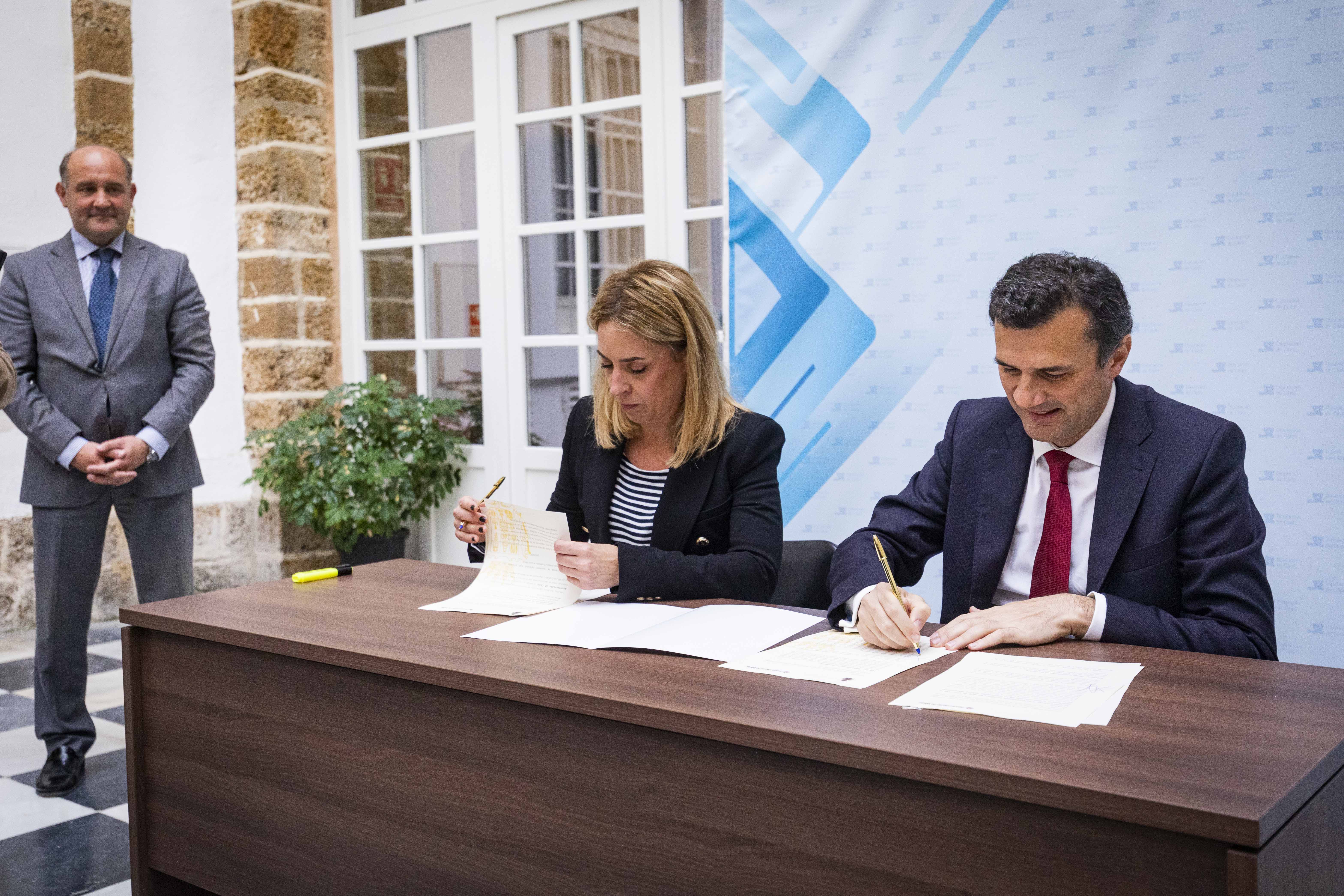 Presidenta y alcalde firman el protocolo de colaboración ante la mirada del concejal de Cádiz Juan José Ortiz.
