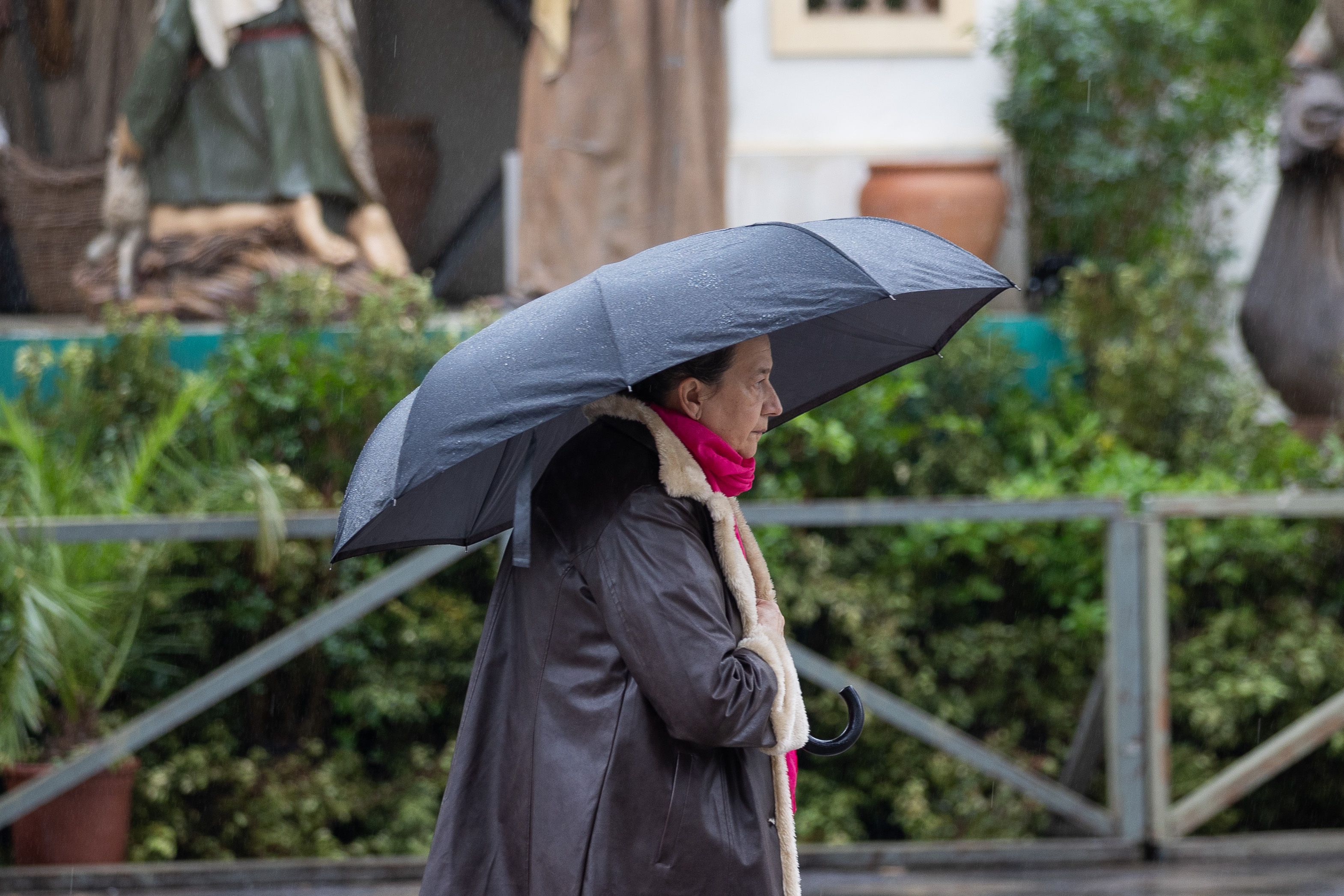 Agua para el puente: llega otro 'desfile' de borrascas. Un transeúnte pasando ante el Nacimiento de Cristina en un día lluvioso.