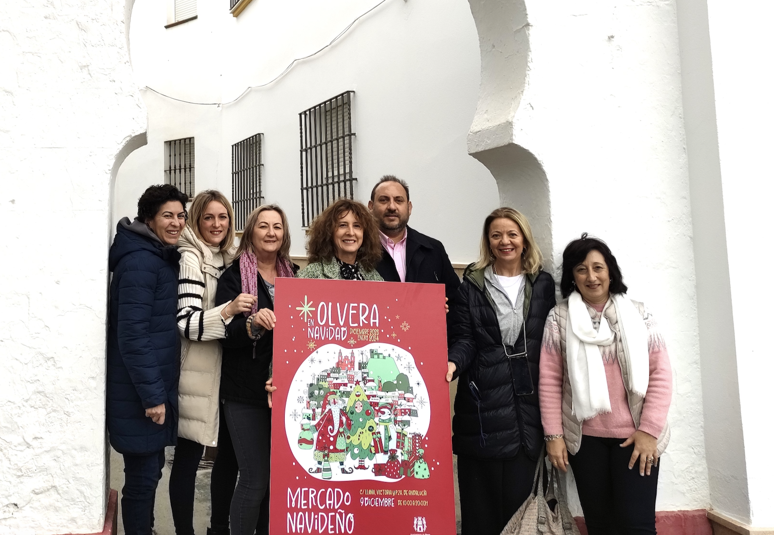 La alcaldesa y delegados junto a comerciantes con el cartel del Mercado Navideño.