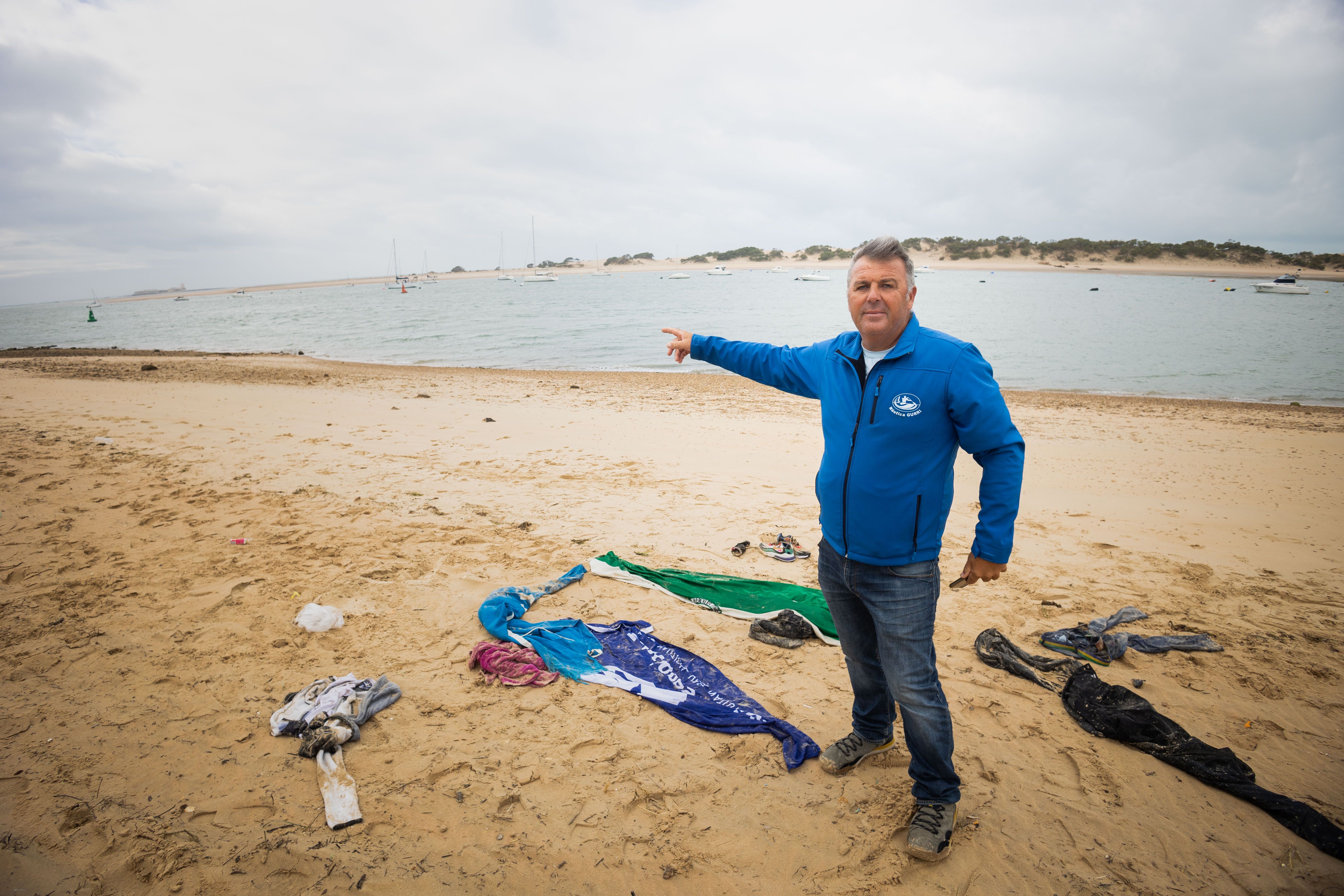 Javier Gutiérrez, con los restos de ropa de los migrantes, señala el lugar donde estuvo a punto de ocurrir la tragedia.