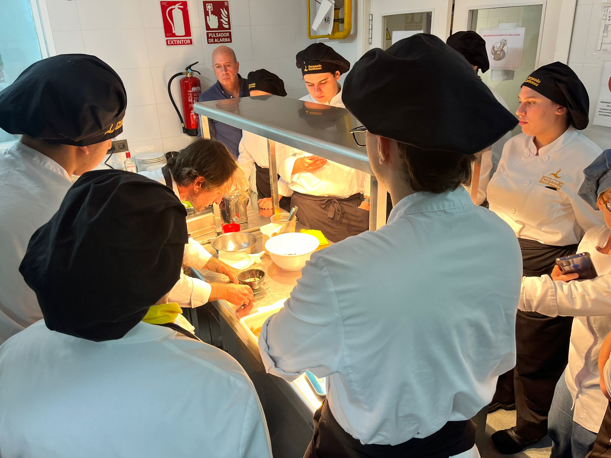 Alumnos de cocina en la cocina rodeado de alumnos.