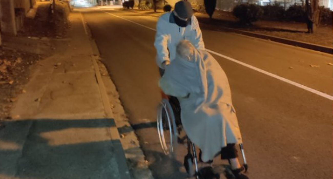 Un hombre de 94 años empuja la silla de ruedas de su mujer tras salir del hospital.