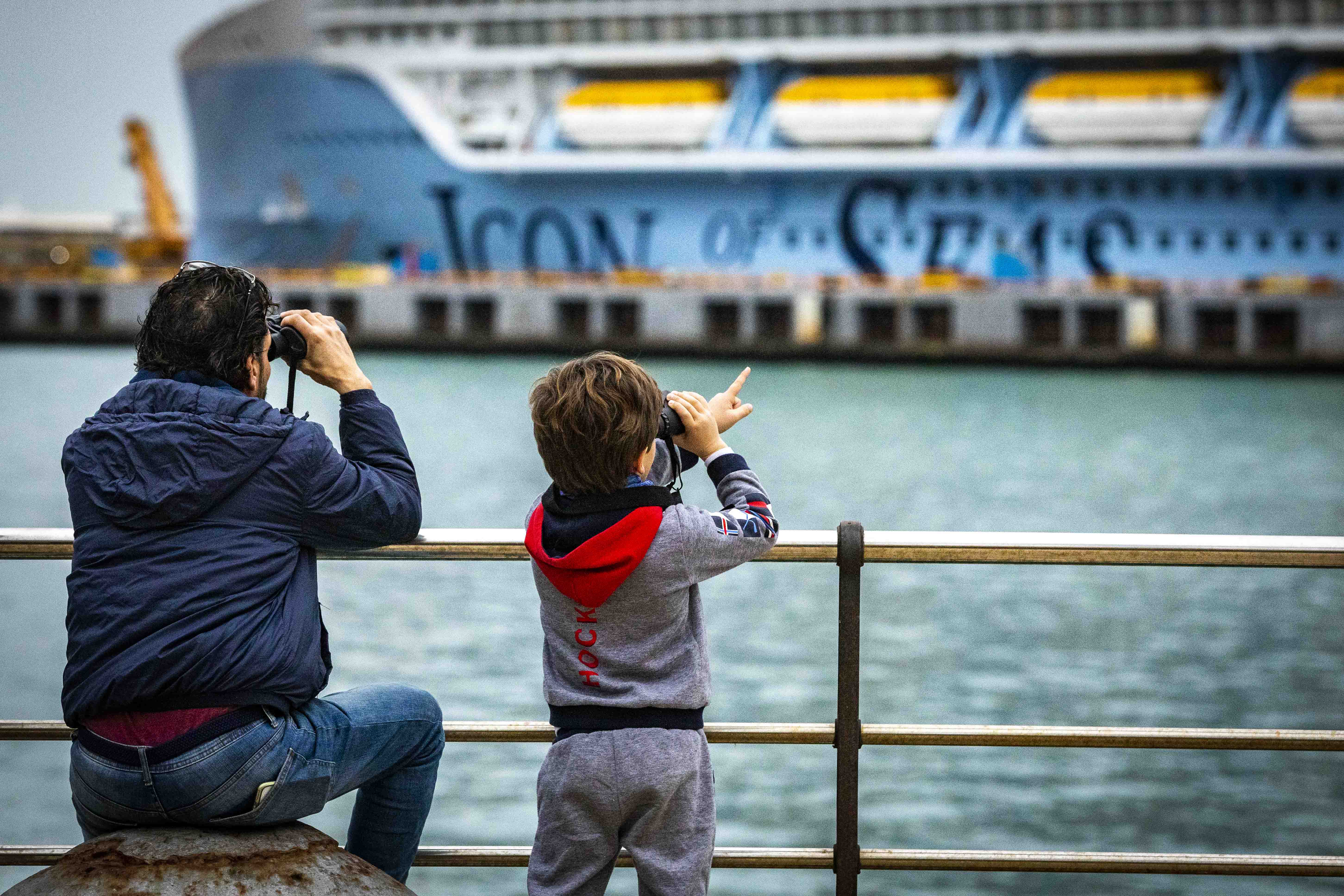 Padre e hijo observan con prismáticos el mayor crucero del mundo.   GERMÁN MESA