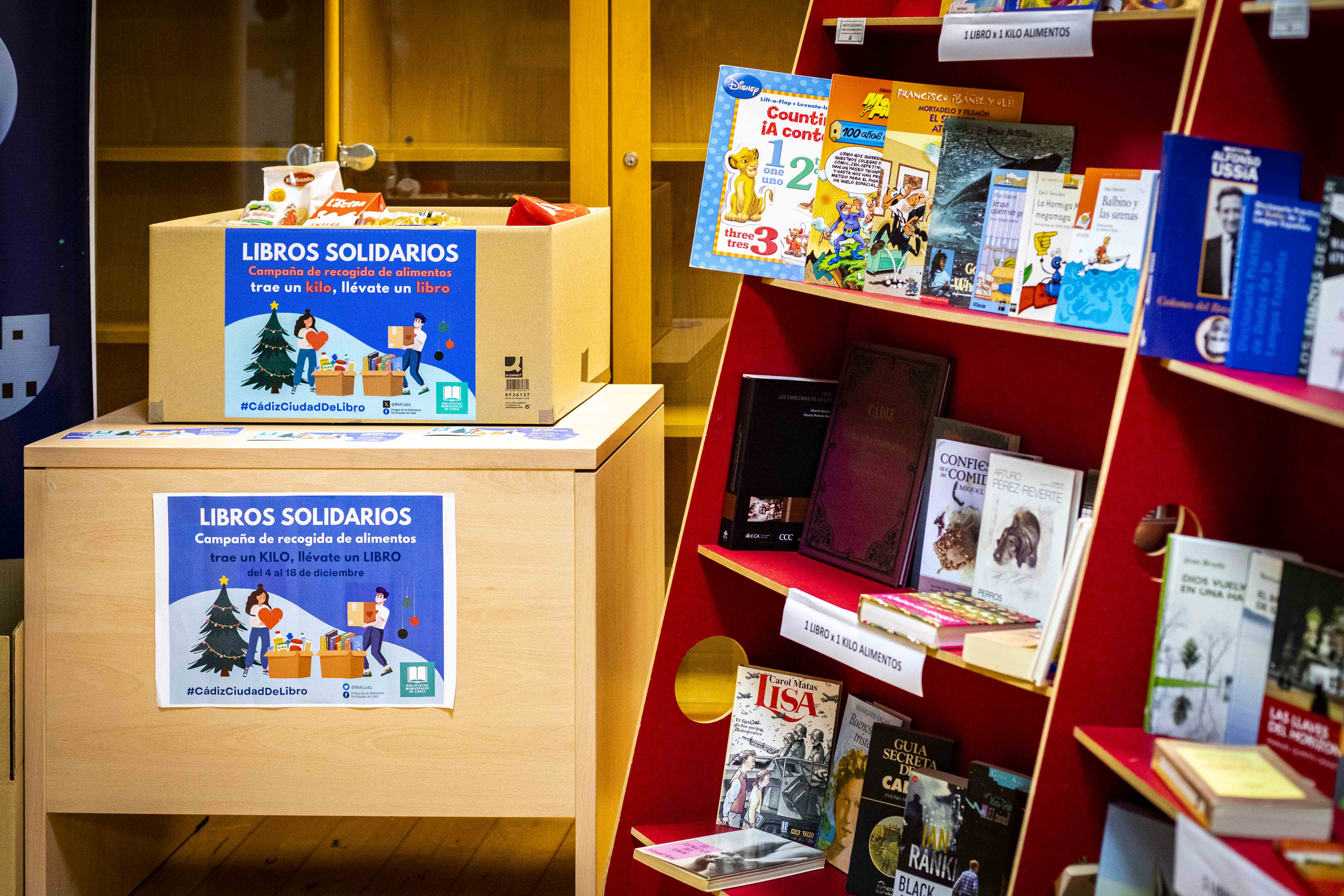 Algunos de los libros disponibles, junto a las cajas para dejar los alimentos, en la biblioteca Adolfo Suárez.   GERMÁN MESA