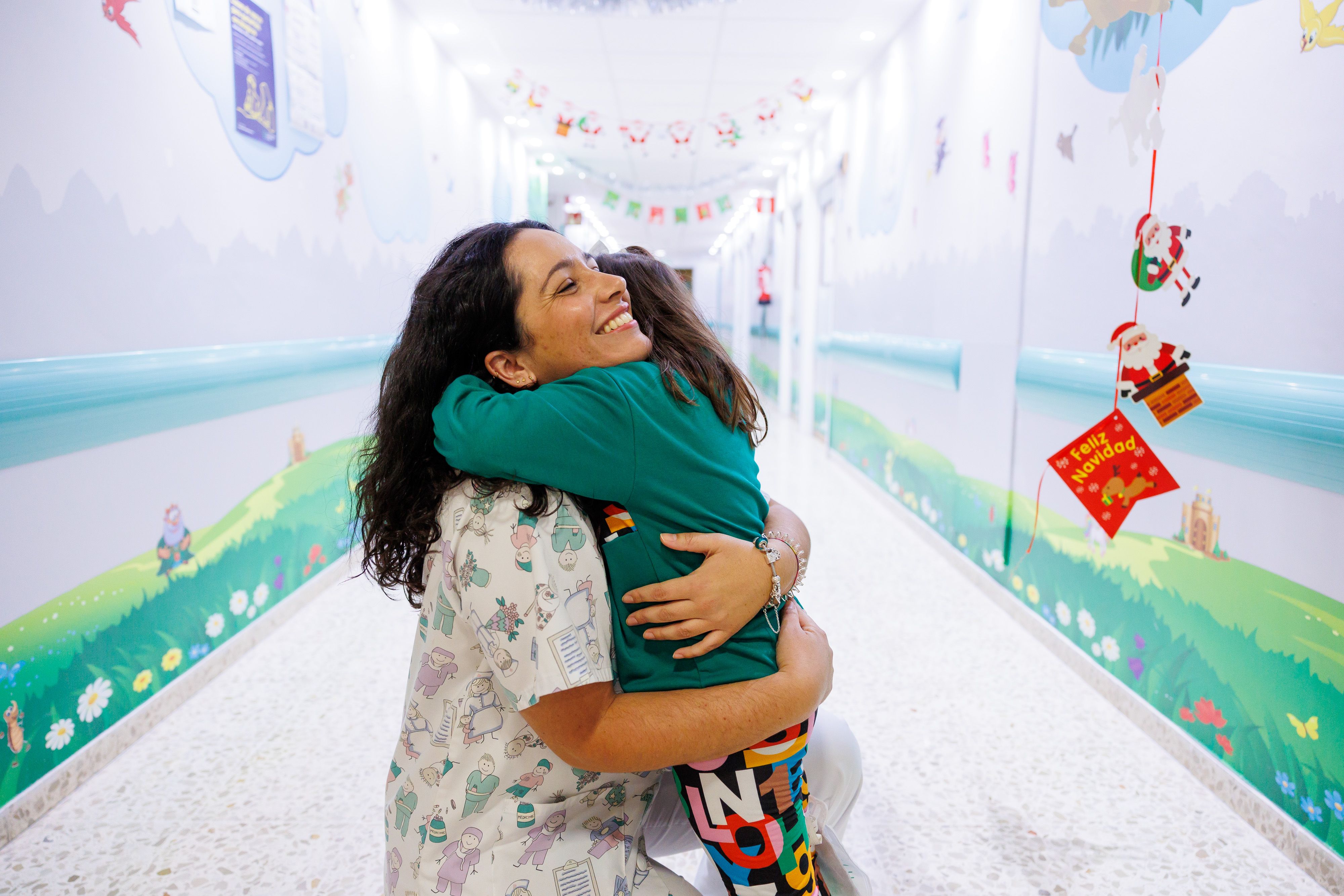 Ana Pérez, maestra del aula hospitalaria del Puerta del Mar de Cádiz, abrazando a una pequeña.