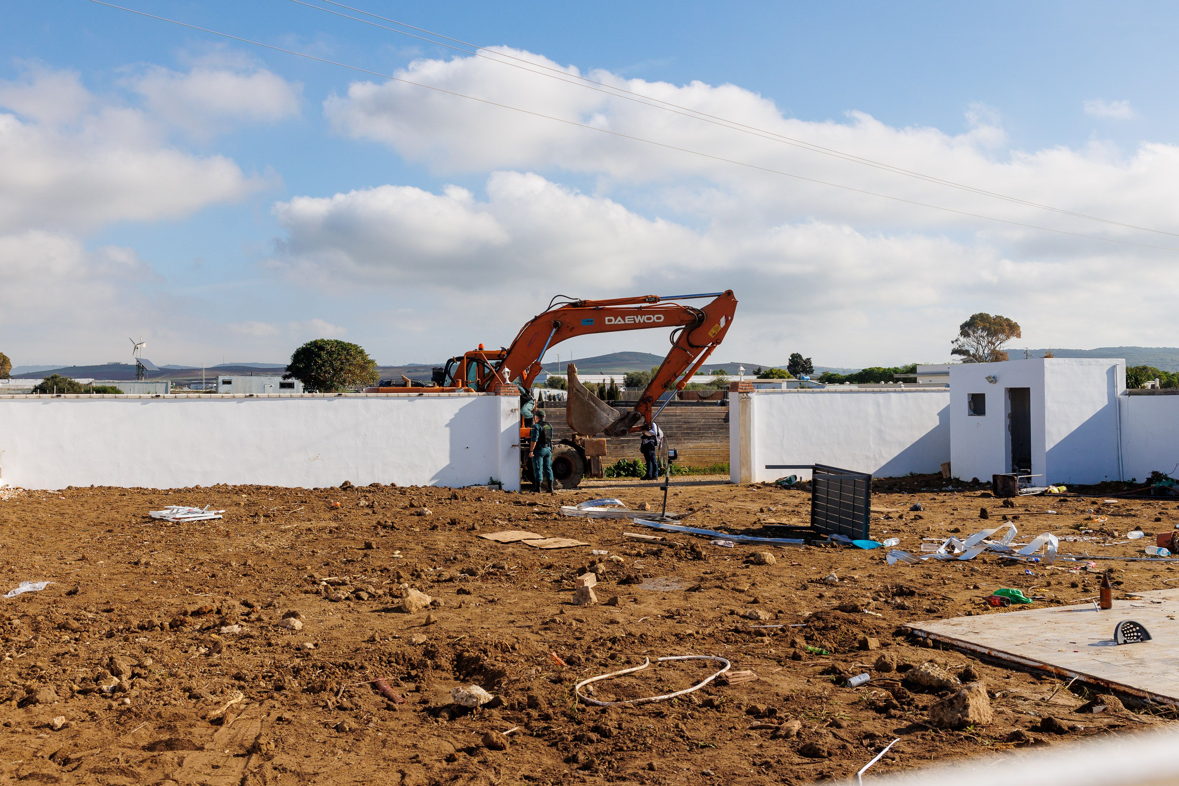La parcela demolida este martes, con los agentes y la excavadora junto a su acceso. 