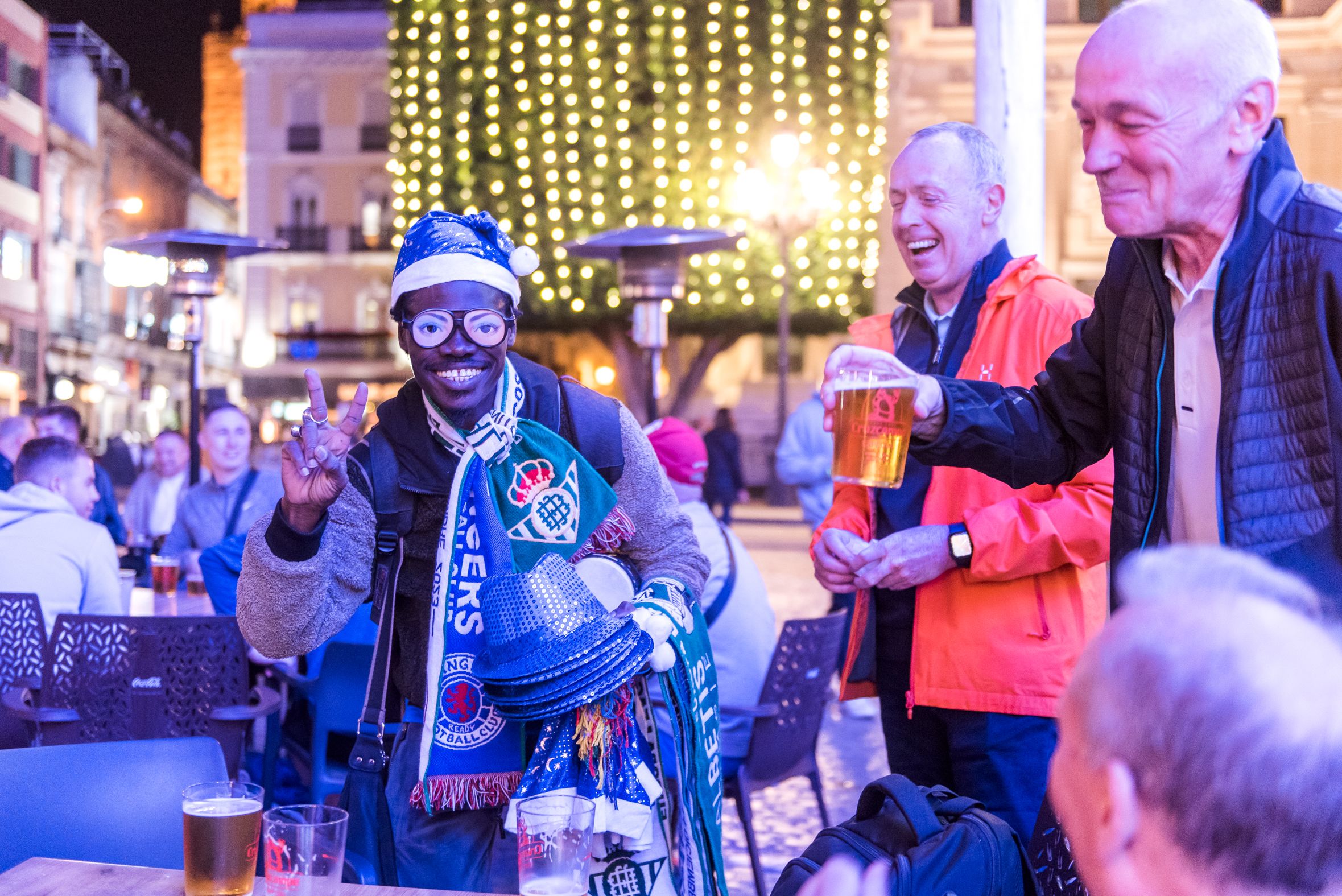 Aficionados escoceses junto a Bamba, senegalés que vende por las calles de Sevilla en Navidad.