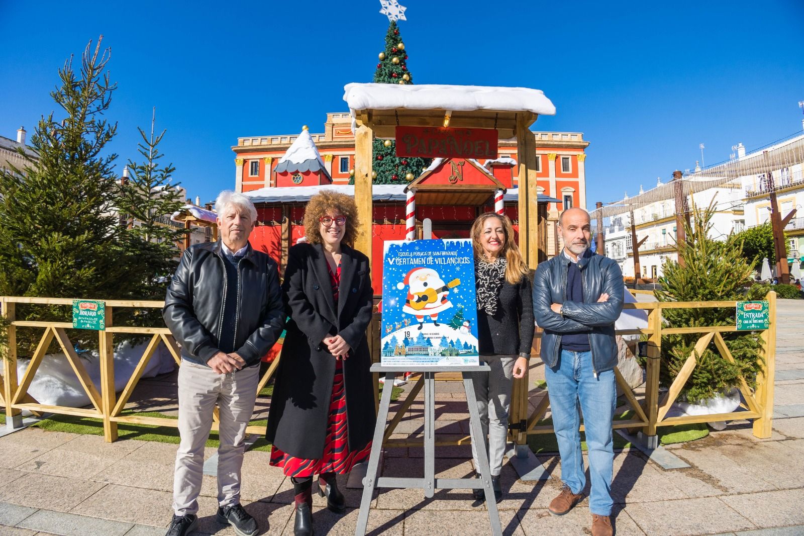 La delegada de Cultura y organizadores junto al cartel del Certamen de Villancicos.
