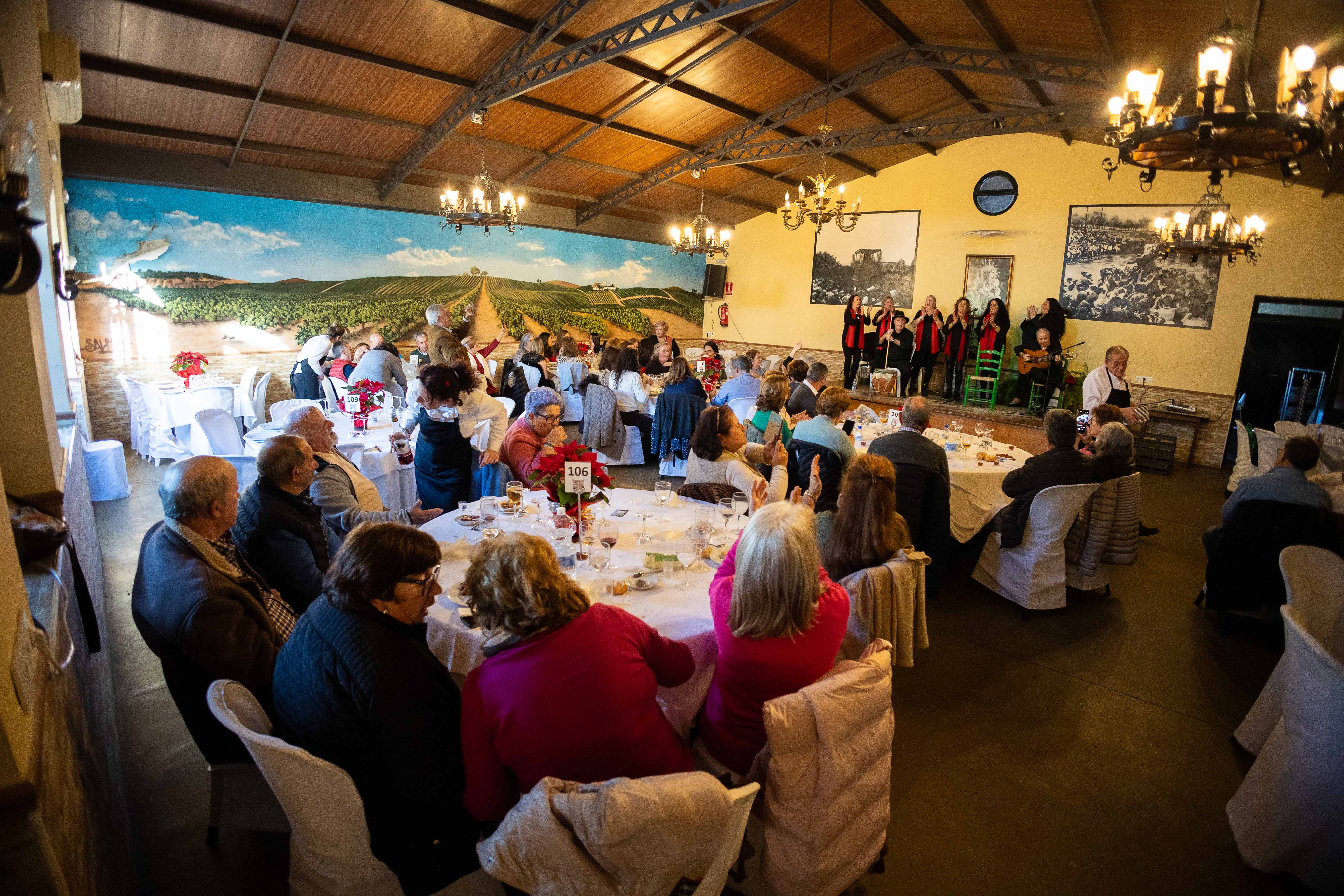 Clientes del mesón rociero Blanca Paloma, comiendo mientras actúa un grupo.