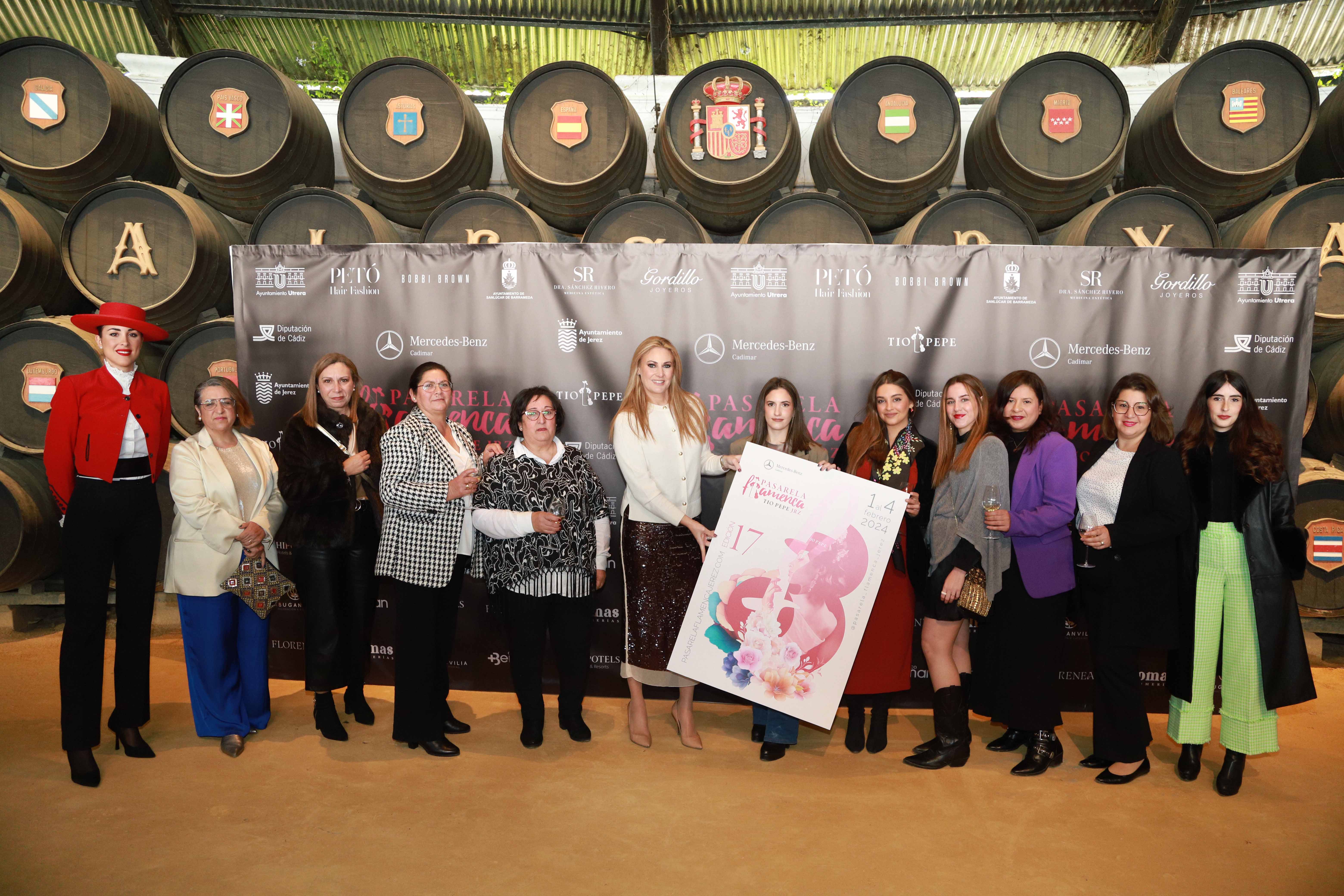 La directora junto a algunas de las diseñadoras participantes, mostrando el cartel de la Pasarela Flamenca.