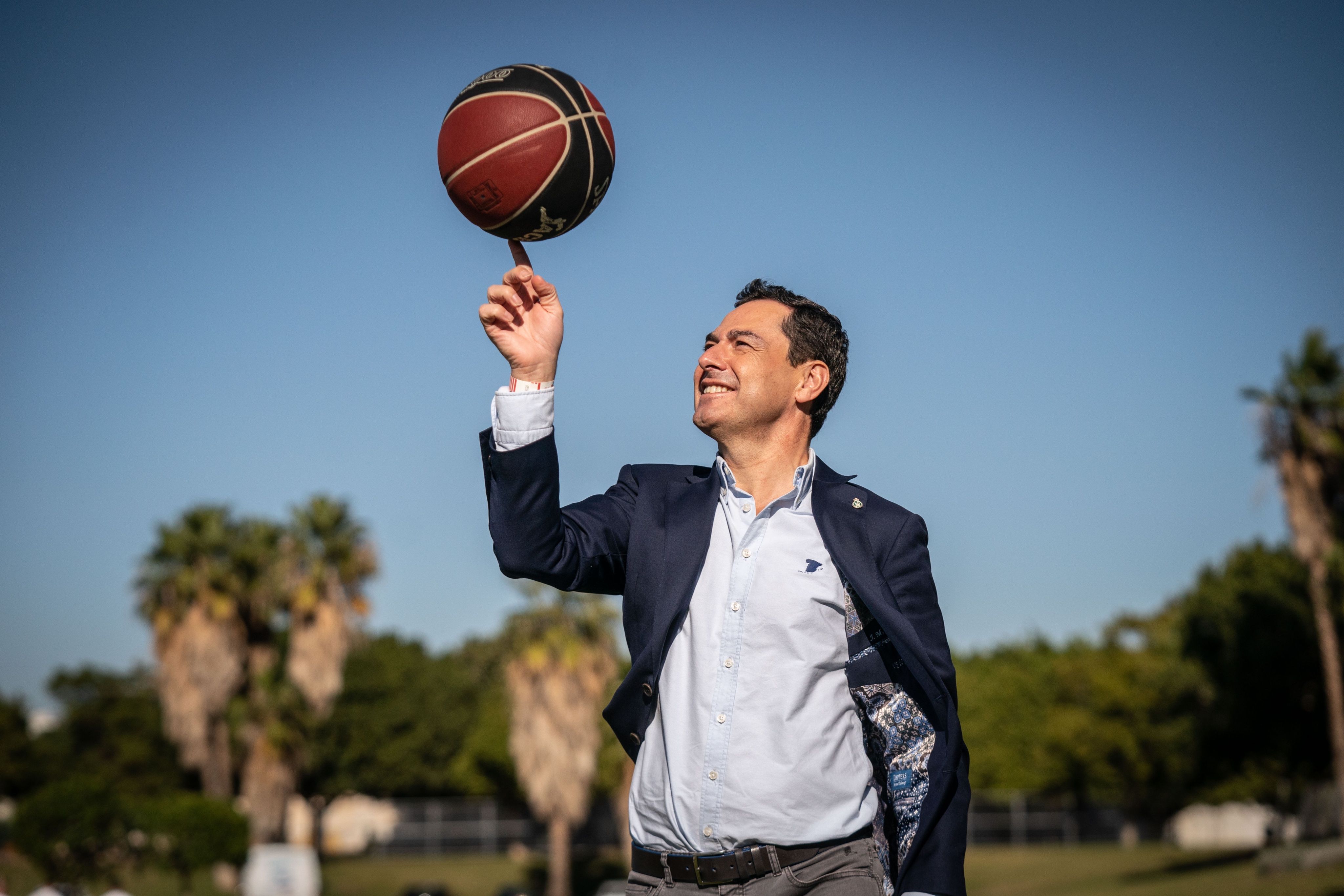 El presidente de Andalucía, Juanma Moreno hace sus pinitos con una pelota de baloncesto, en una imagen reciente.