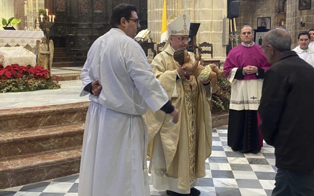 El obispo dando a besar a la imagen del Niño Jesus en la pasada Misa del Gallo.