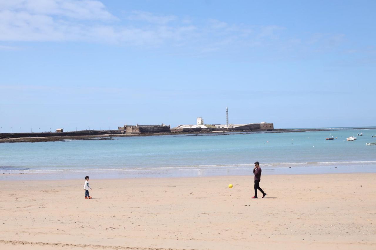 Un padre pasea por una playa de Cádiz, durante el confinamiento. FOTO: JUAN CARLOS TORO