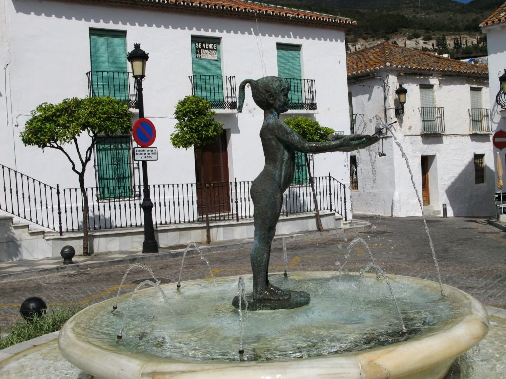 Una escultura de una niña en una fuente.  