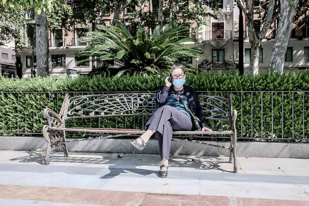 Una señora, con mascarilla, sentada en un banco. FOTO: JOSÉ LUIS TIRADO (joseluistirado.es)