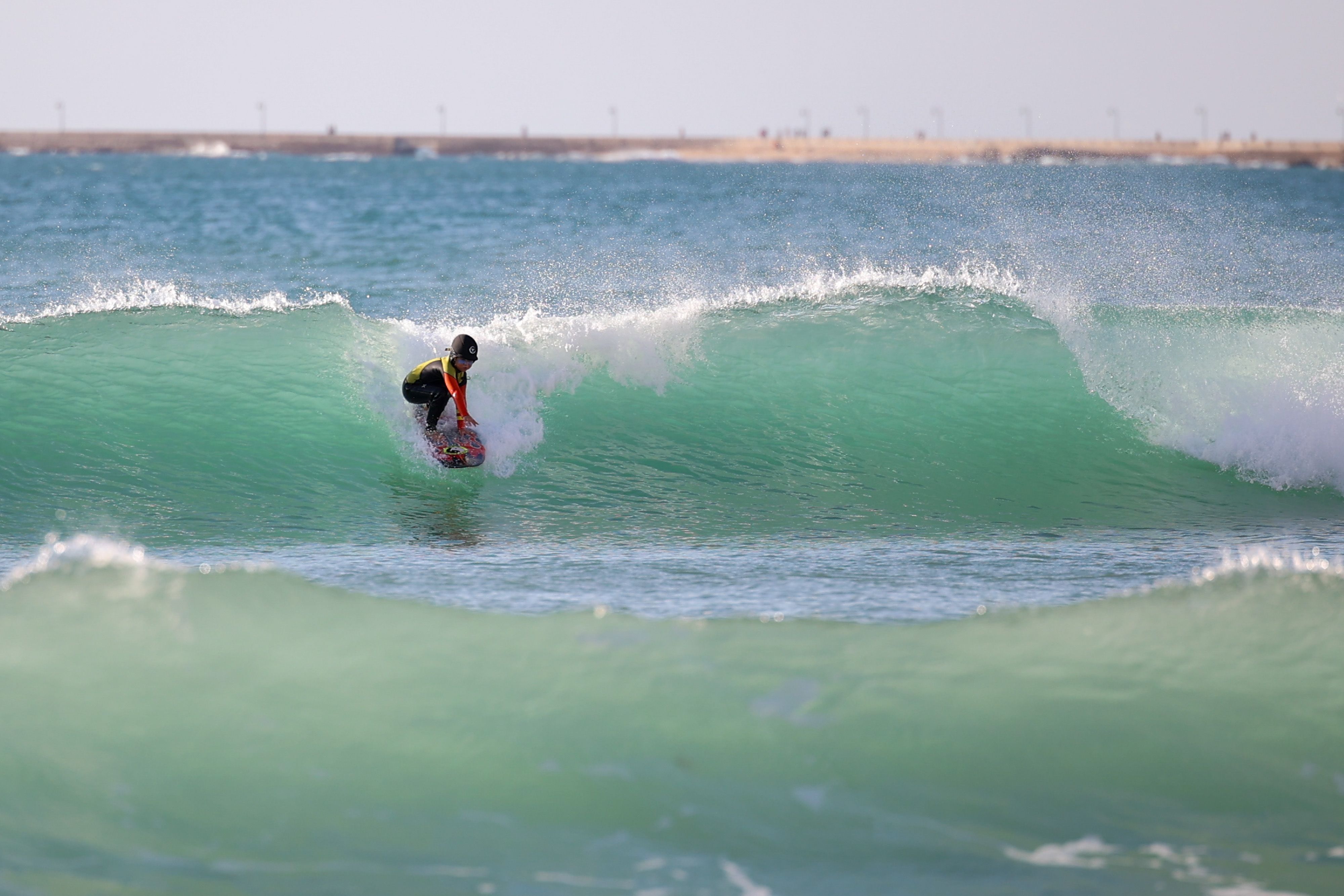 La pequeña surfista cogiendo olas en su playa de Cádiz.  
