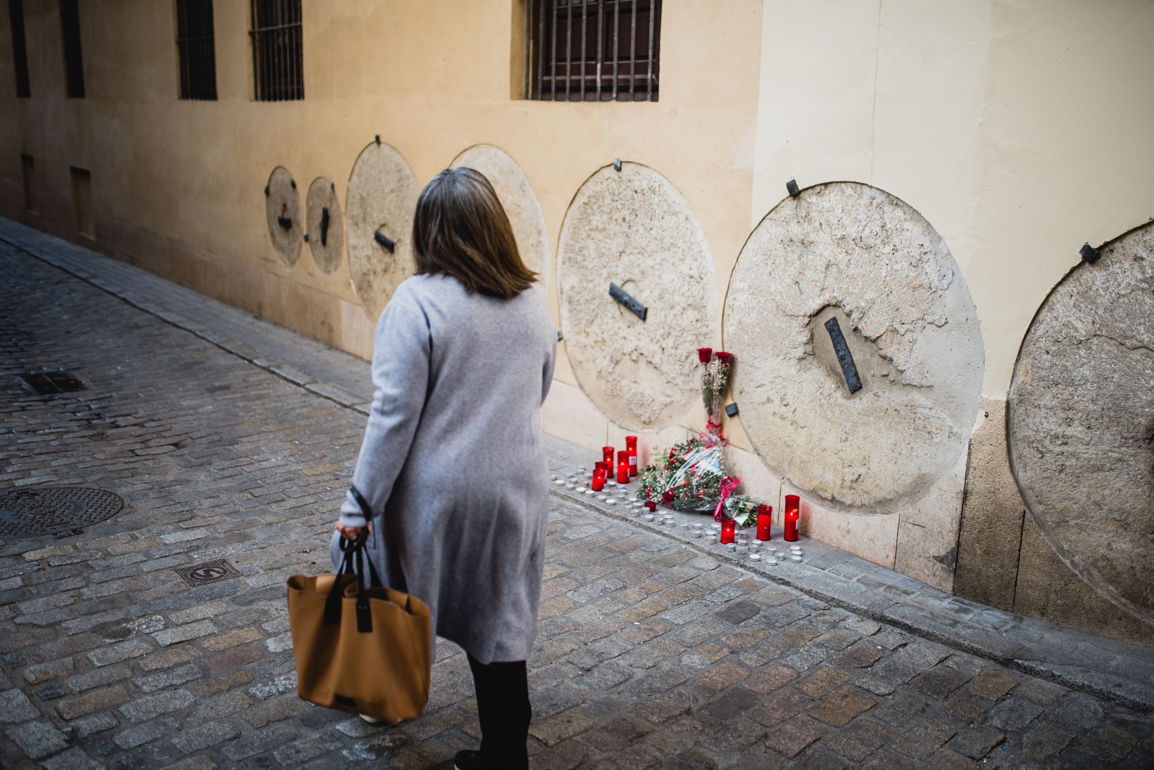 Una mujer pasea frente a velas y flores por el lugar donde mataron a Alberto Jiménez-Becerril y Ascensión García Ortiz, en la calle Don Remondo.