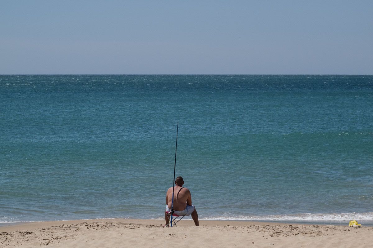 Un hombre, pescando en una playa de Rota.