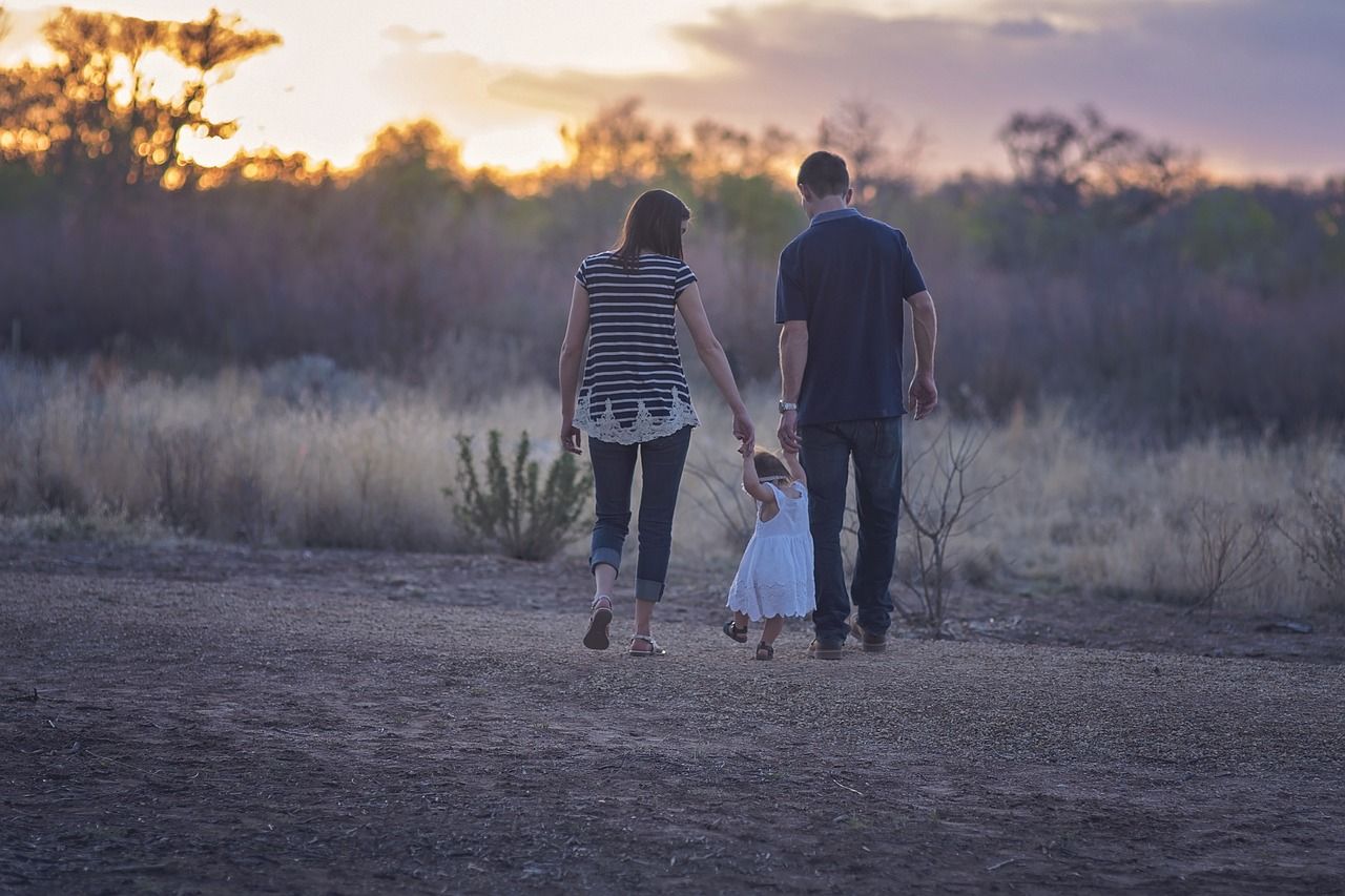 Una familia, con su papá y su mamá, pasean con una niña pequeña.