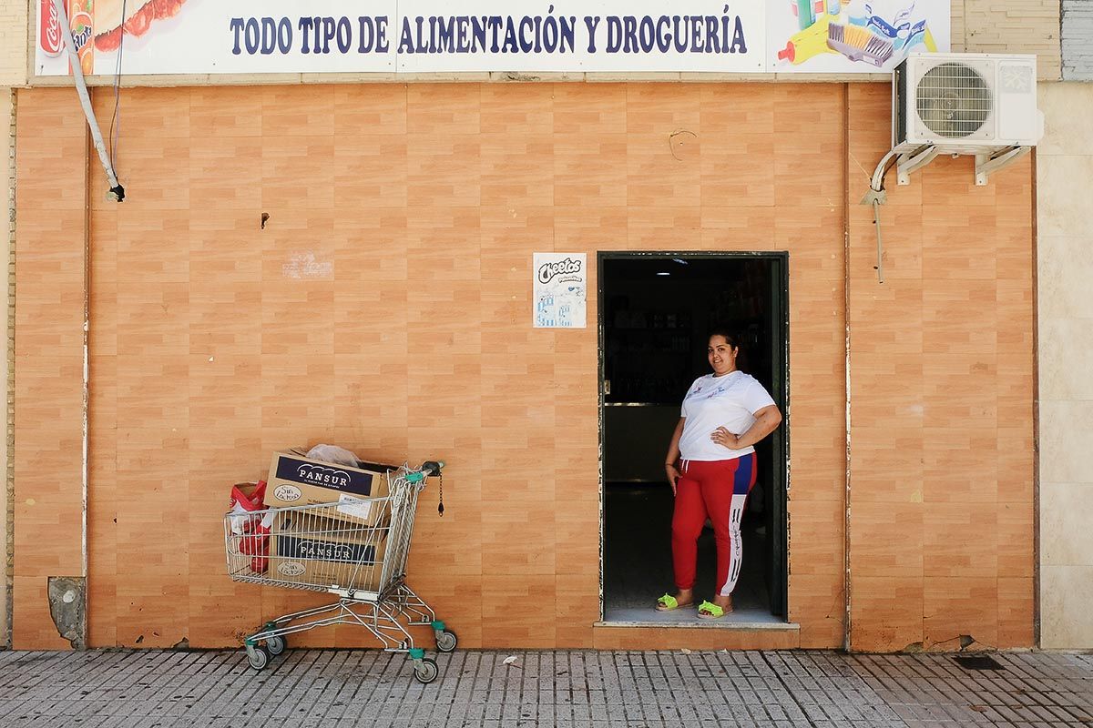 Aída en la puerta de la tienda de comestibles en la que trabaja como dependienta, en el Polígono Sur de Sevilla. FOTO: JOSÉ LUIS TIRADO 