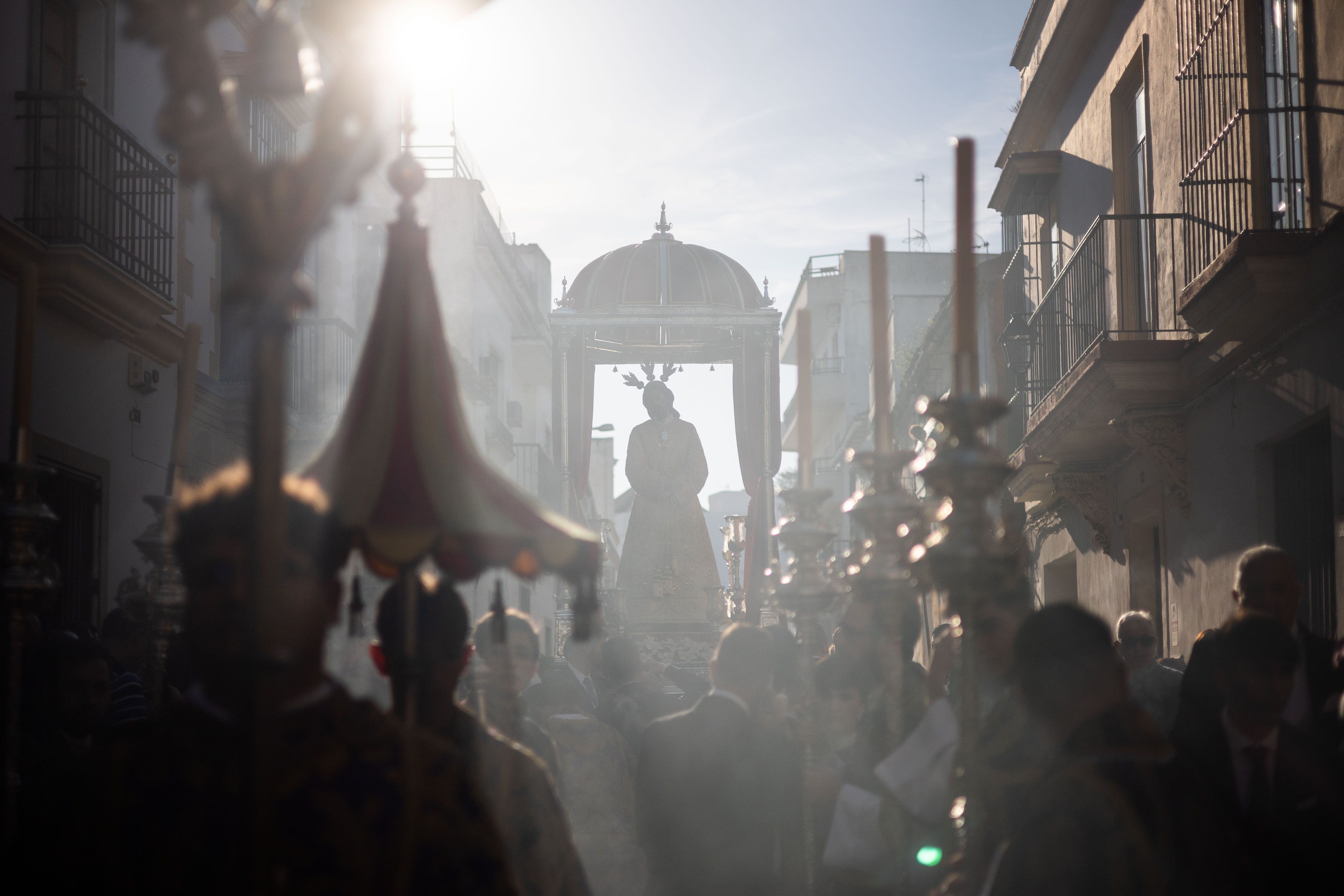 Las Hermandades de Jerez celebran su Vía Crucis. El Señor del Consuelo en calle Merced de ida a la Catedral con el sol detrás.