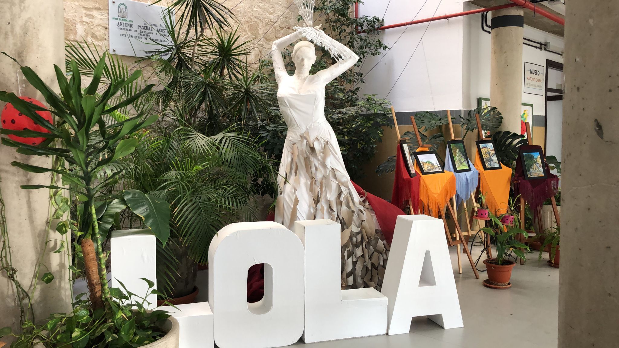 Una escultura de Lola Flores, en el IES Santa Isabel de Hungría, con cuadros al fondo de una de las exposiciones de la semana cultural.