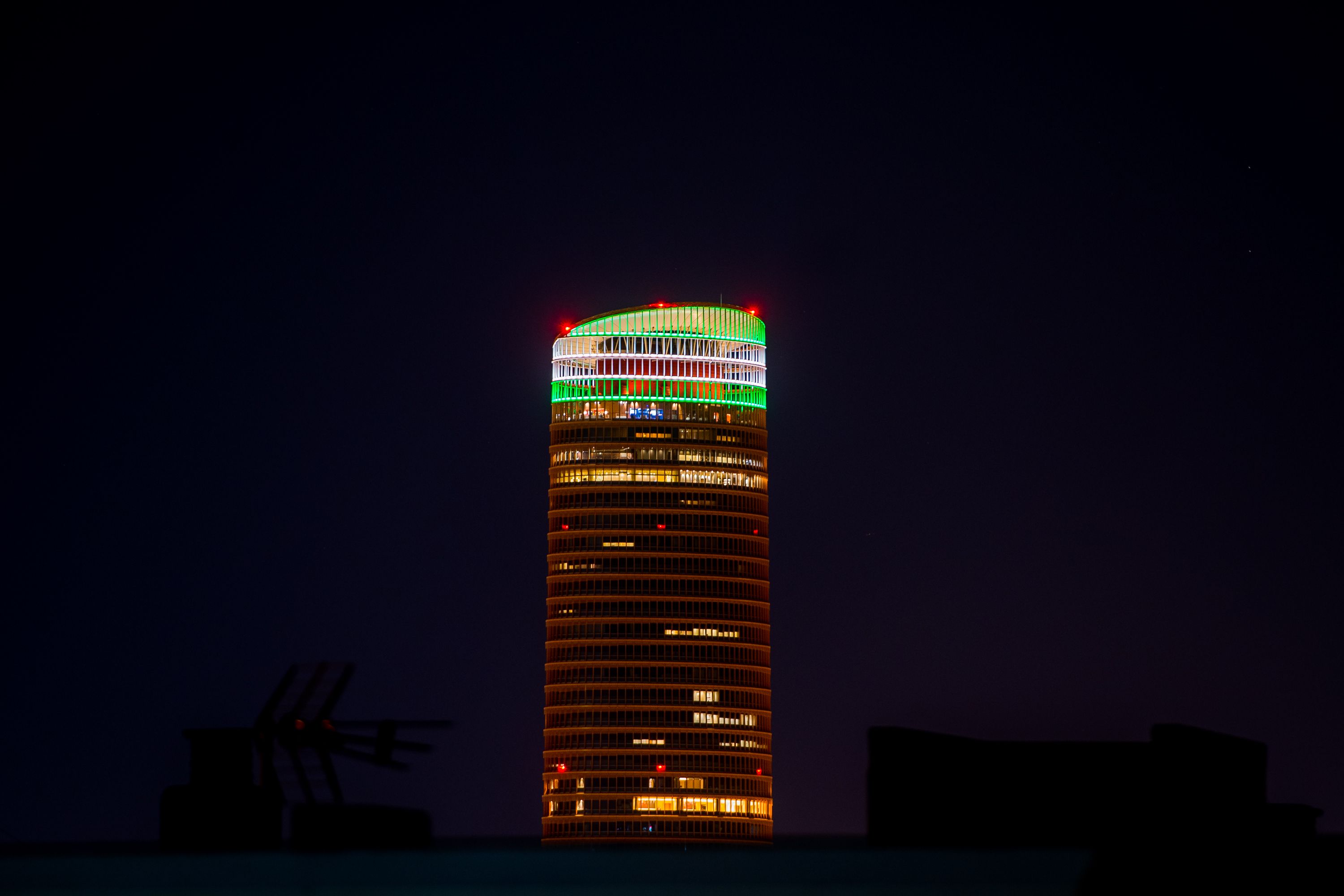 La Torre Sevilla iluminada con los colores de la bandera de Andalucía.