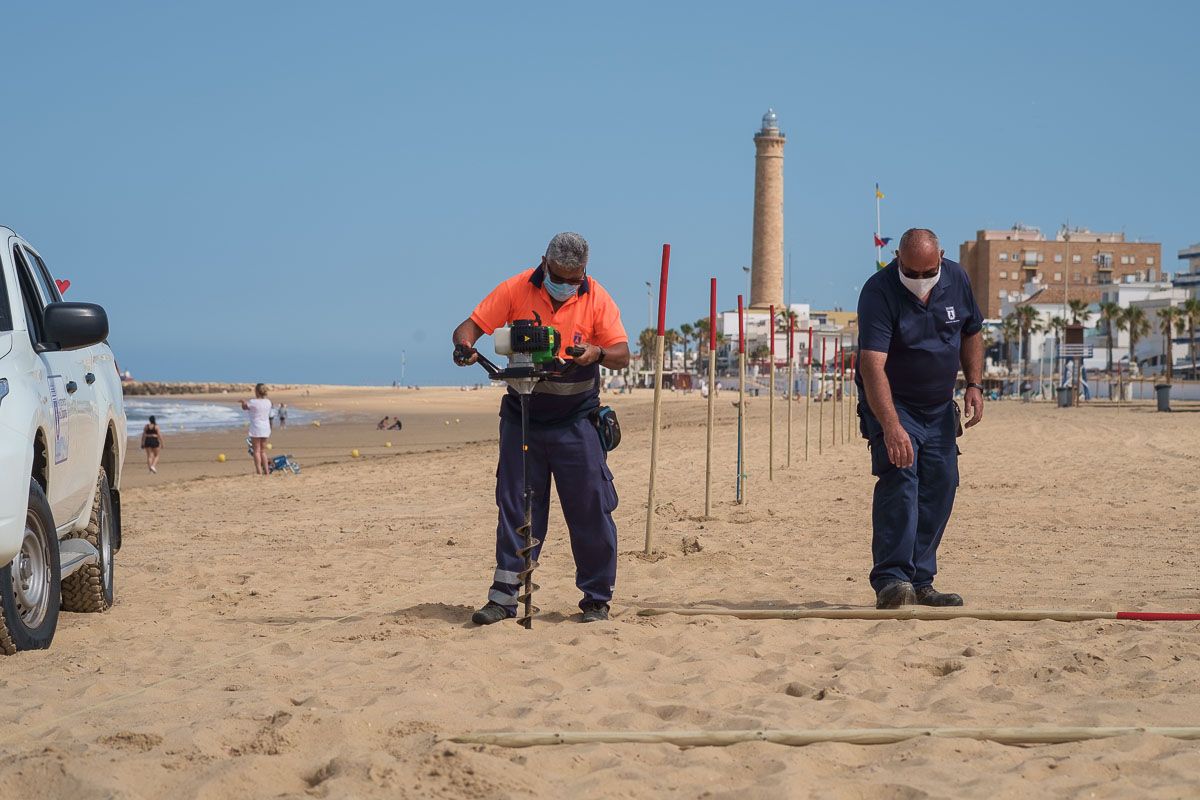 Operarios parcelan la playa de Chipiona para mantener la distancia de seguridad. FOTO: MANU GARCÍA