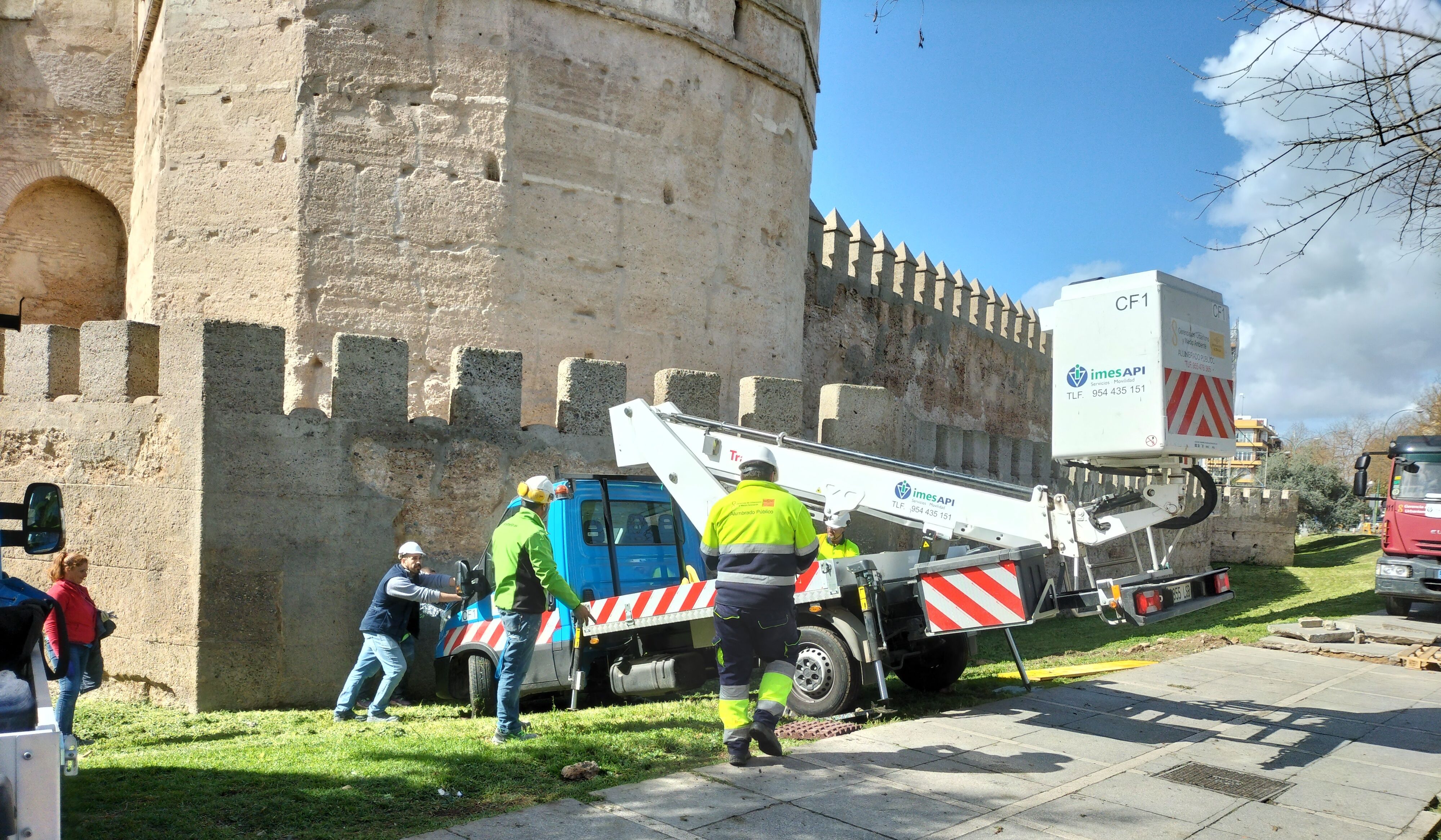 Los operarios, tratando de sacar el vehículo encallado en las murallas de la Macarena.