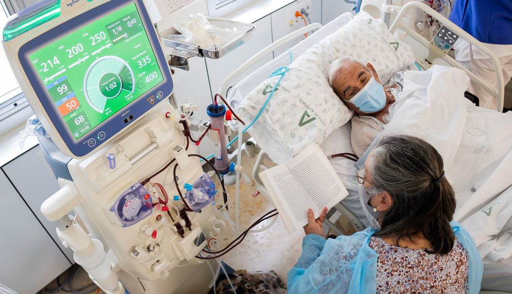 Mercedes, voluntaria del proyecto 'Medicina para el alma', lee en voz alta a Pedro durante su sesión de hemodiálisis.