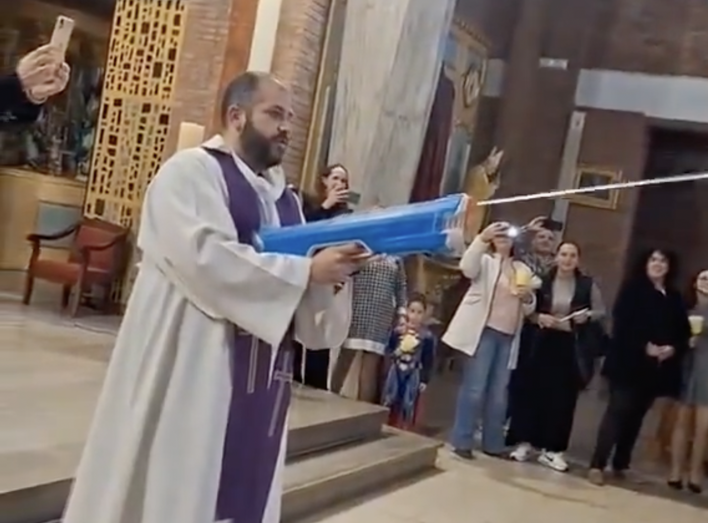 El cura salesiano que bendice a los niños y niñas con una pistola de agua.