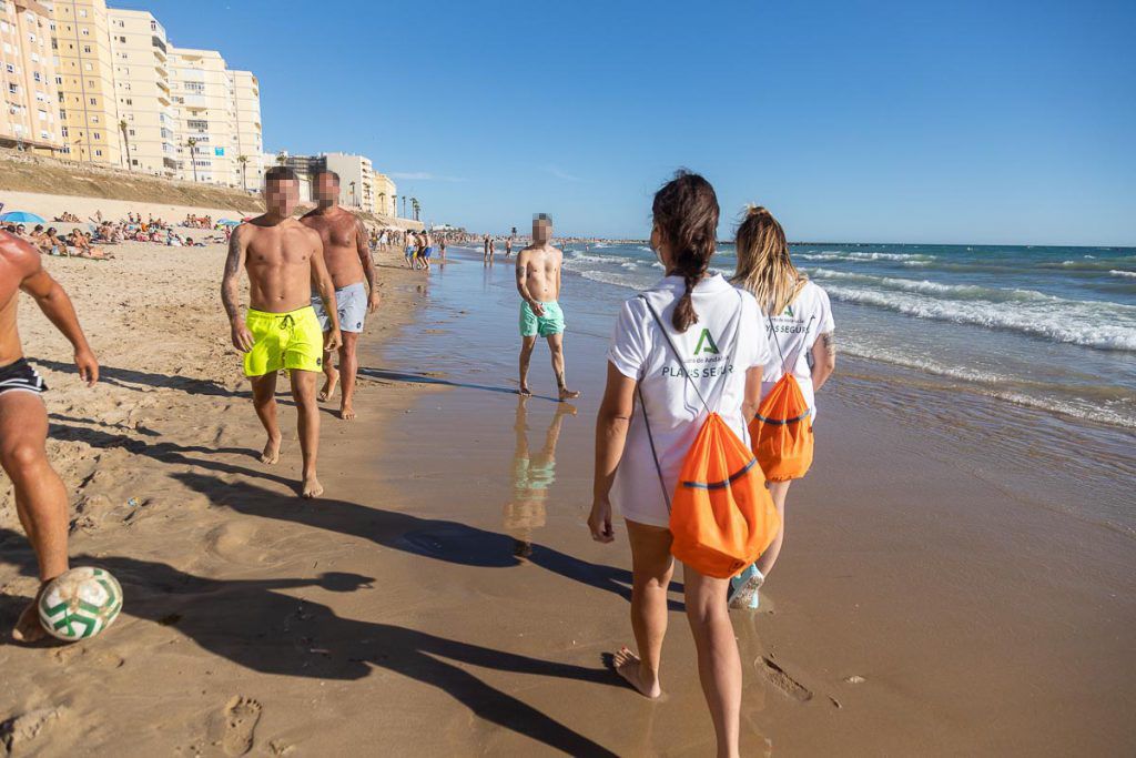 Jóvenes juegan a la pelota mientras auxiliares de playa pasan a su lado en Santa María del Mar. FOTO: JUAN CARLOS TORO