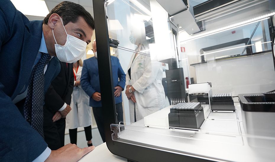 El presidente de la Junta, Juan Manuel Moreno, contemplando una estación ruborizada que realiza PCR.